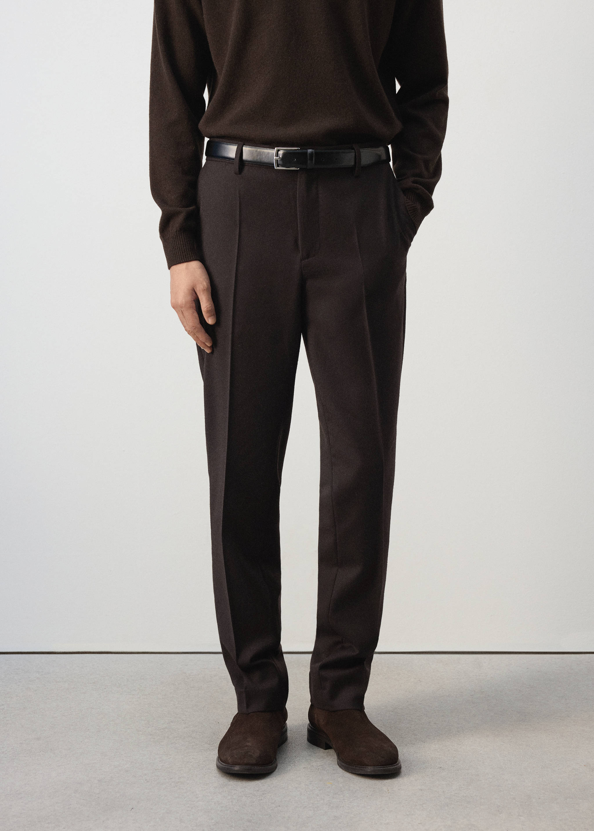 Dark brown tailored trousers with straight legs and pressed creases.