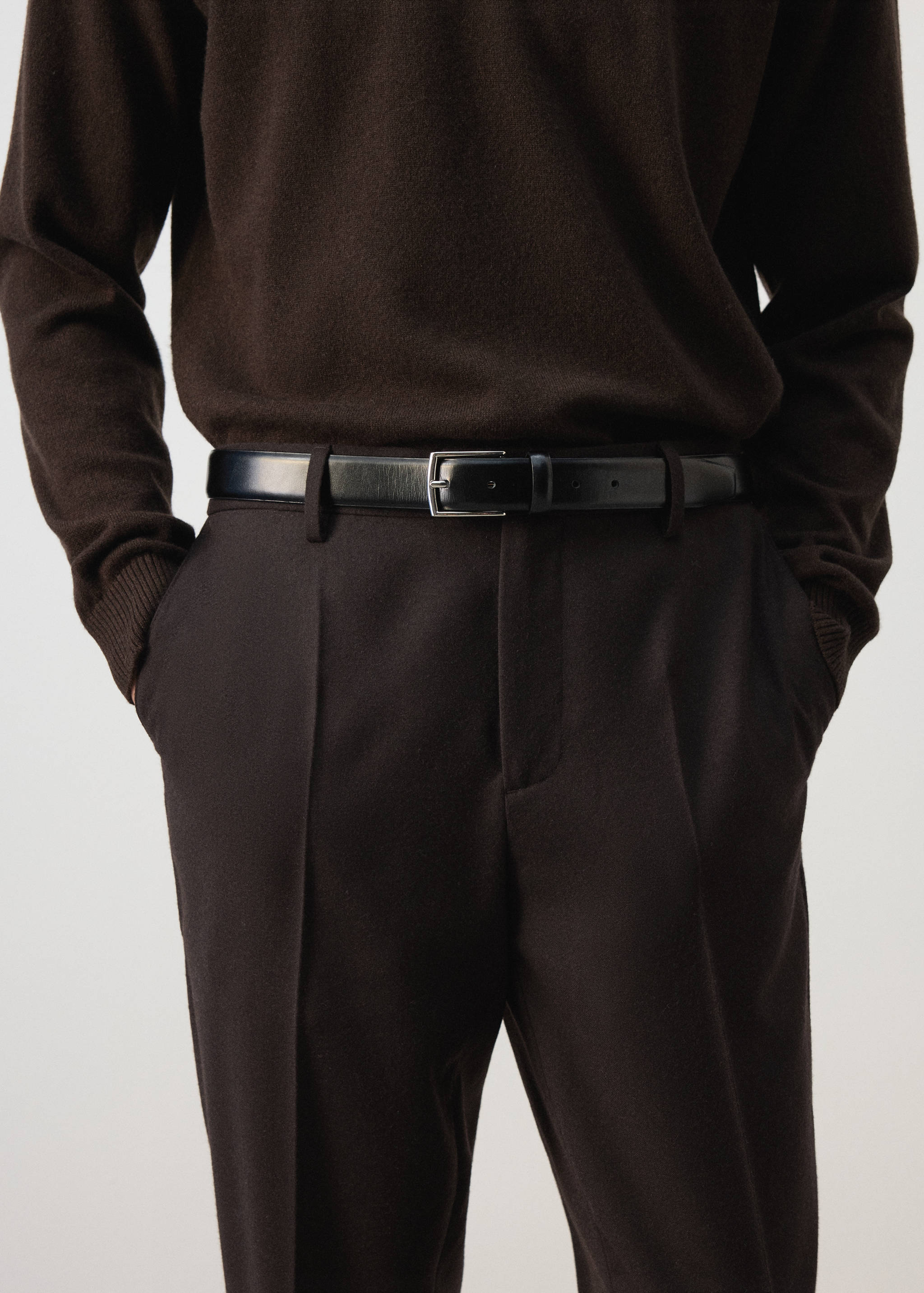 Dark brown trousers with a black leather belt and silver buckle.