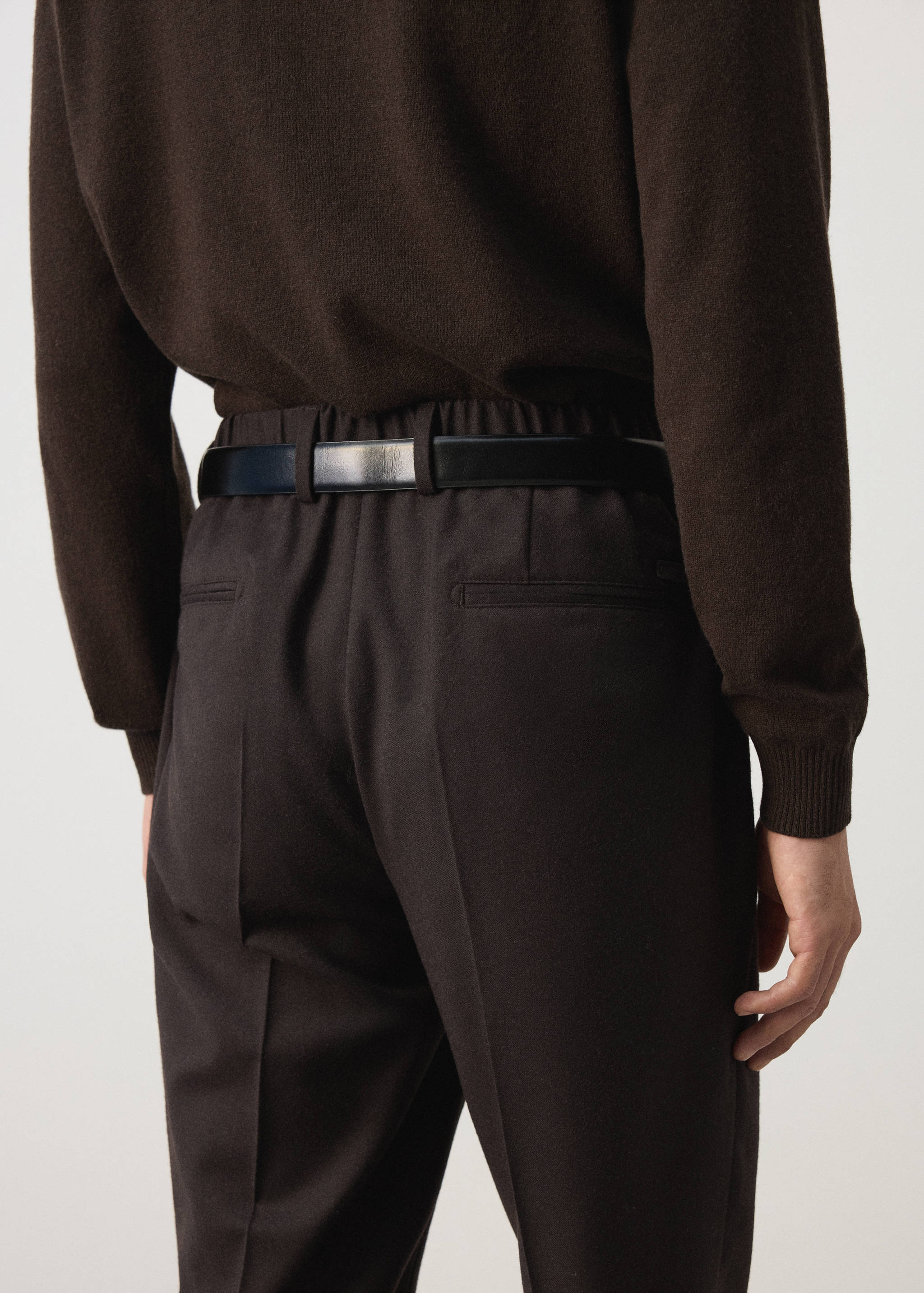 Dark brown trousers with an elasticated waistband and belt loops, back view