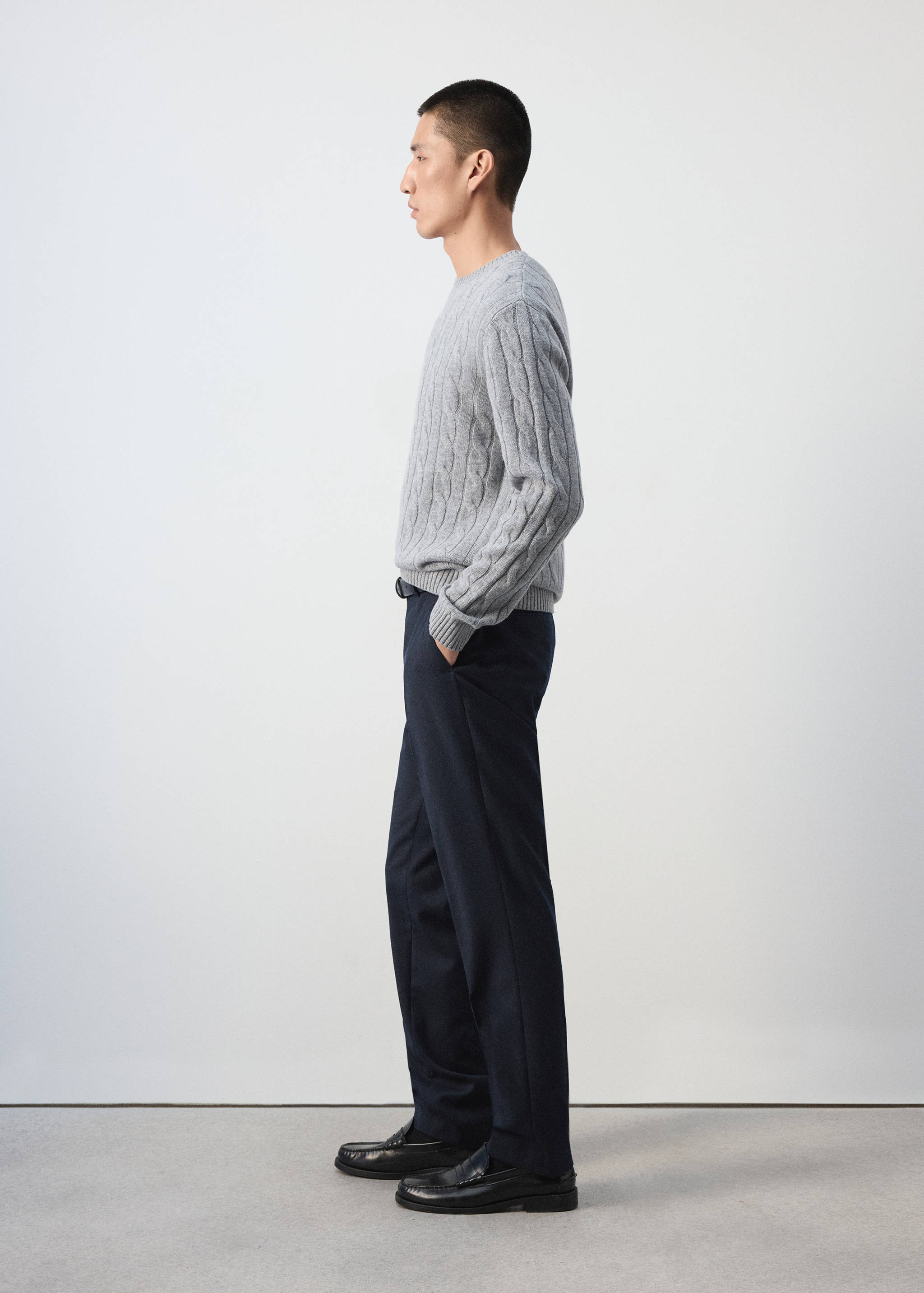 Dark navy blue straight-leg trousers worn with a grey cable-knit sweater.