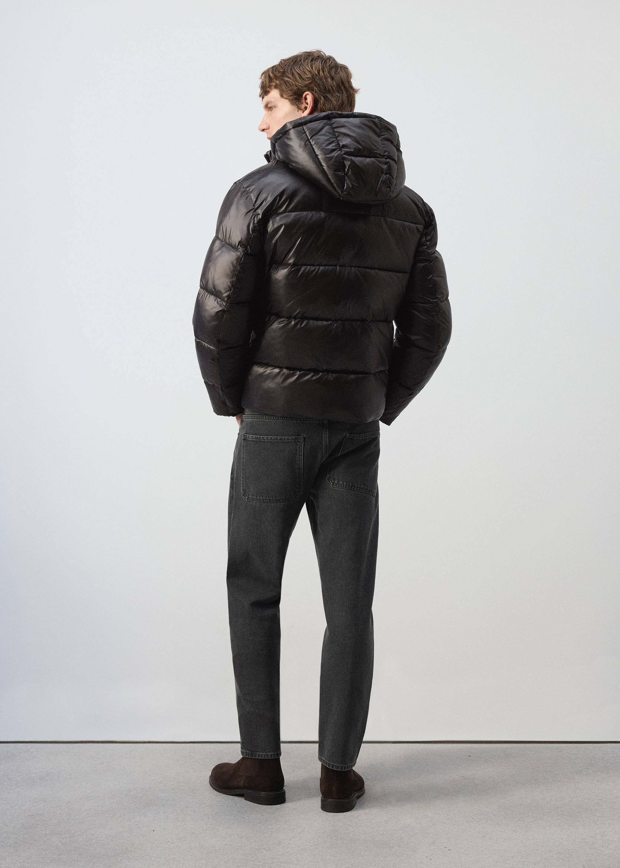 Black quilted anorak with a hood, back view.