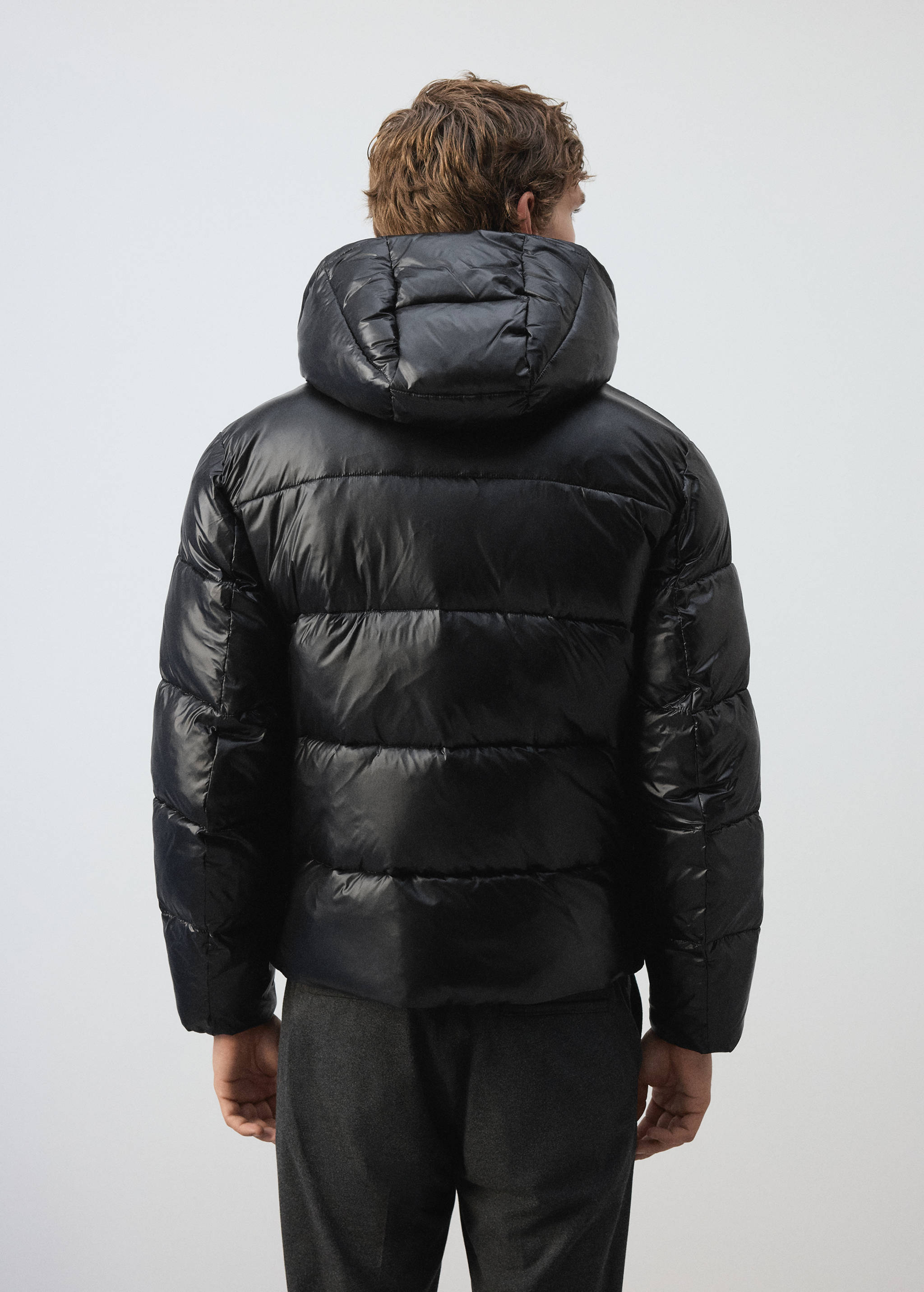 Black quilted anorak with a hood, viewed from the back.