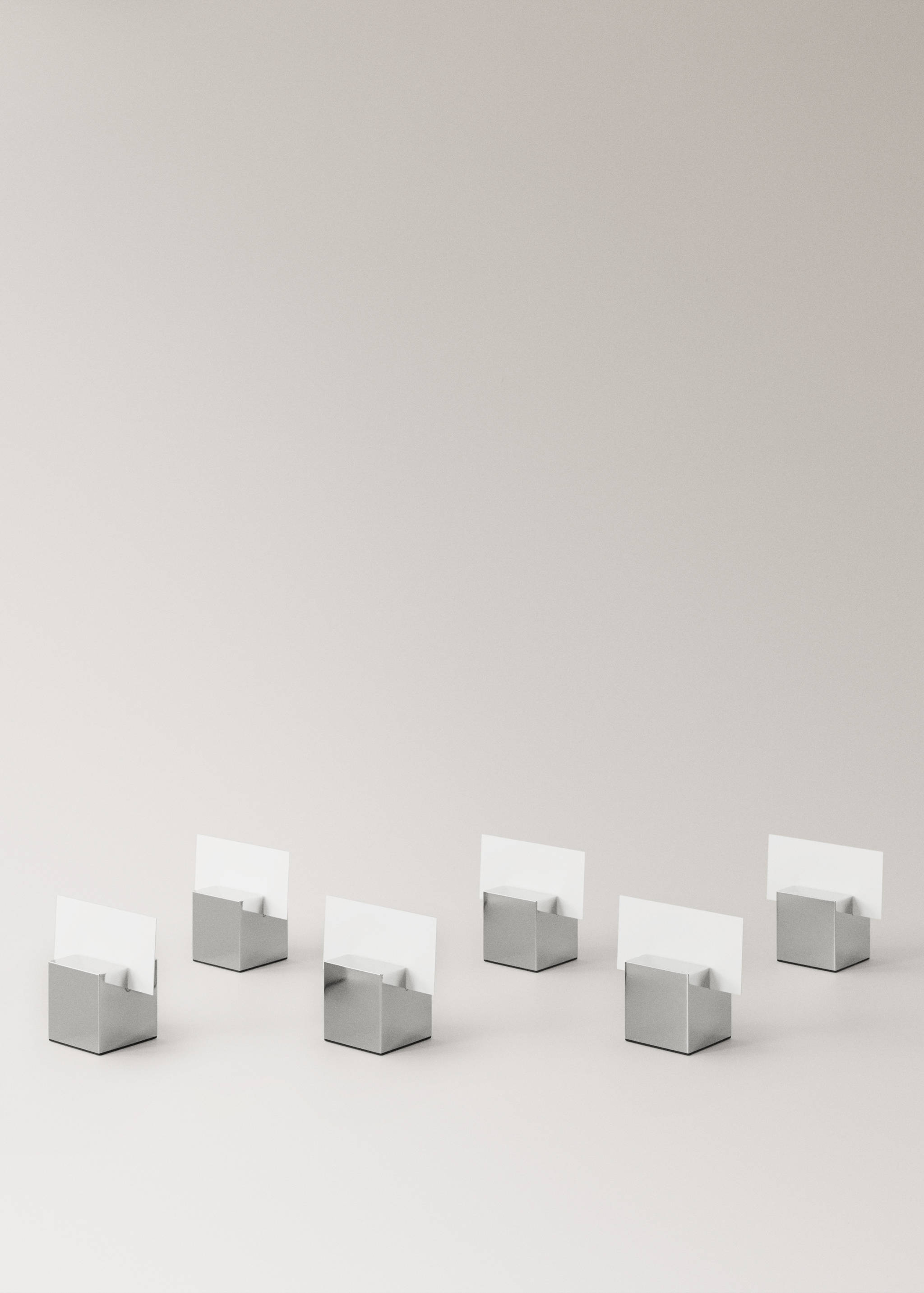 Set of six metallic silver-coloured cube card holders with white cards.