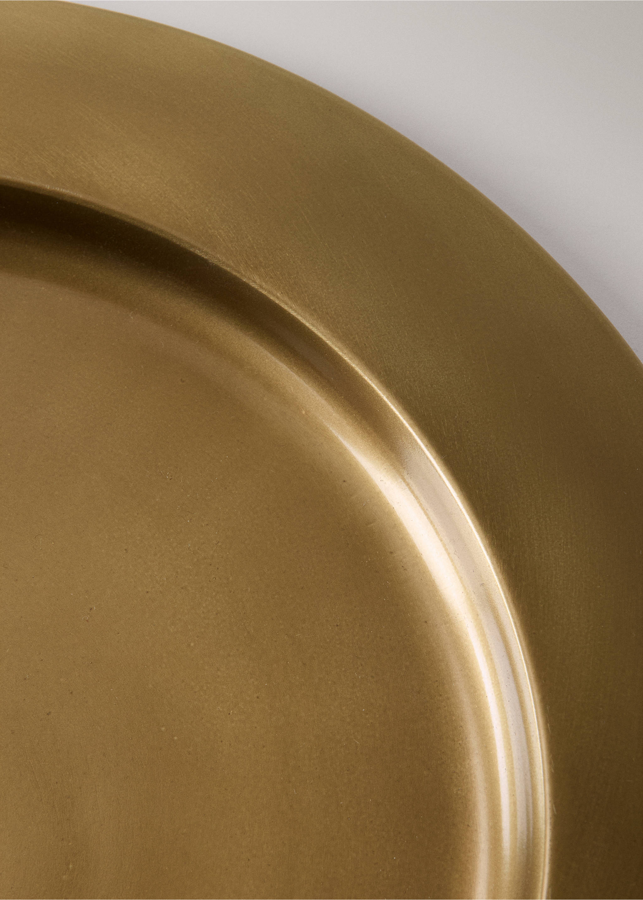 Close-up of a gold-coloured plate with a brushed metallic finish., Gold. Ref: 37017894-00.