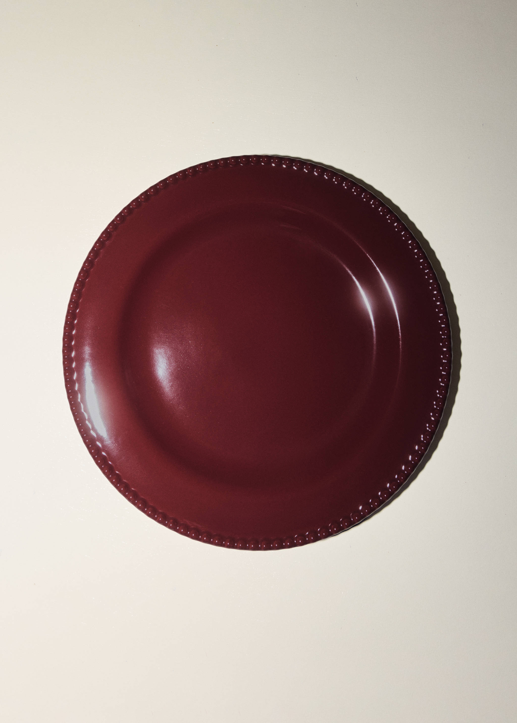 Glossy burgundy plate with a textured beaded rim.