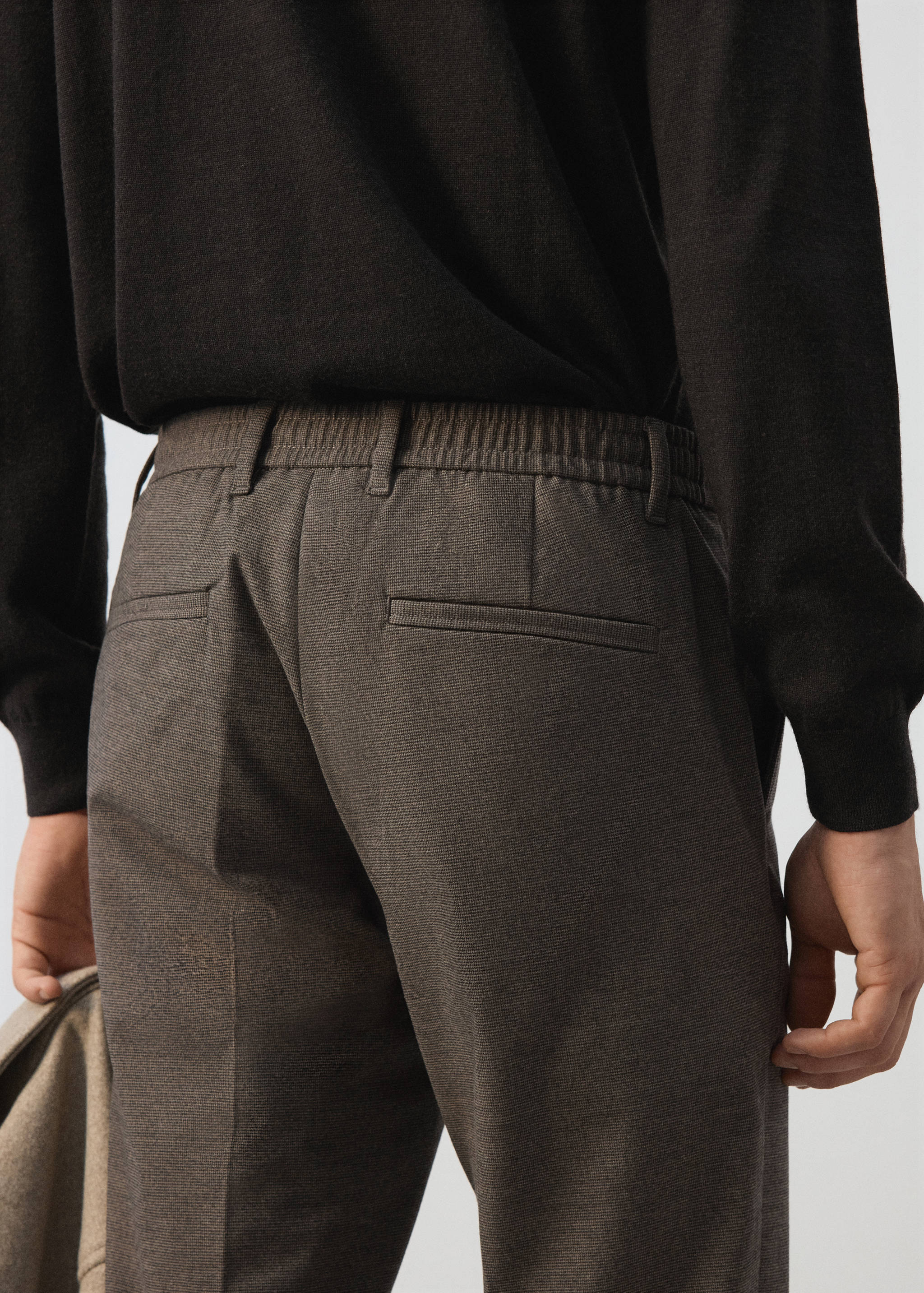 Close-up of the back of dark brown trousers with an elasticated waistband.