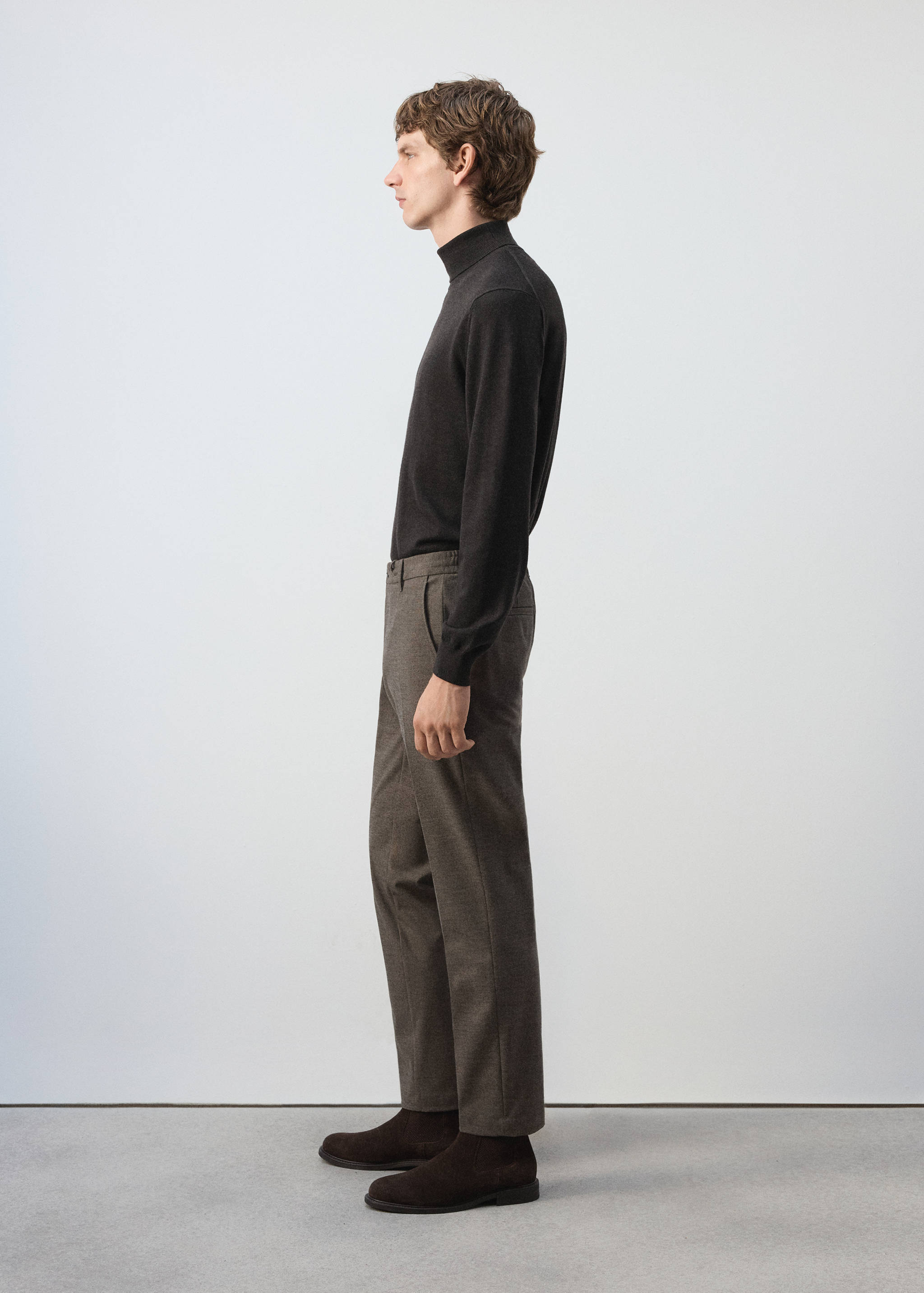 Brown trousers in a straight-leg tailored fit, styled with a dark brown turtleneck.