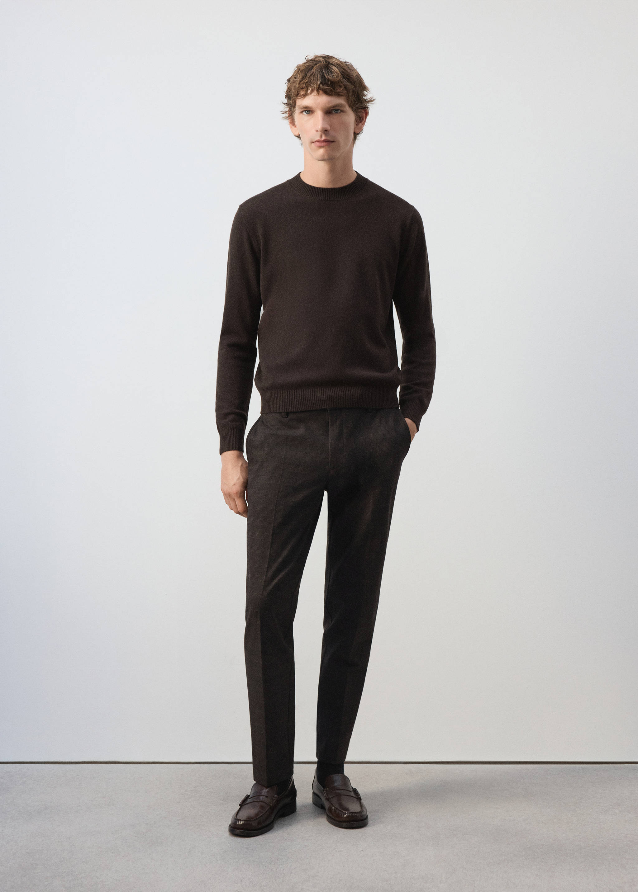 Dark brown tailored trousers with a straight fit, styled with a matching crew neck sweater.