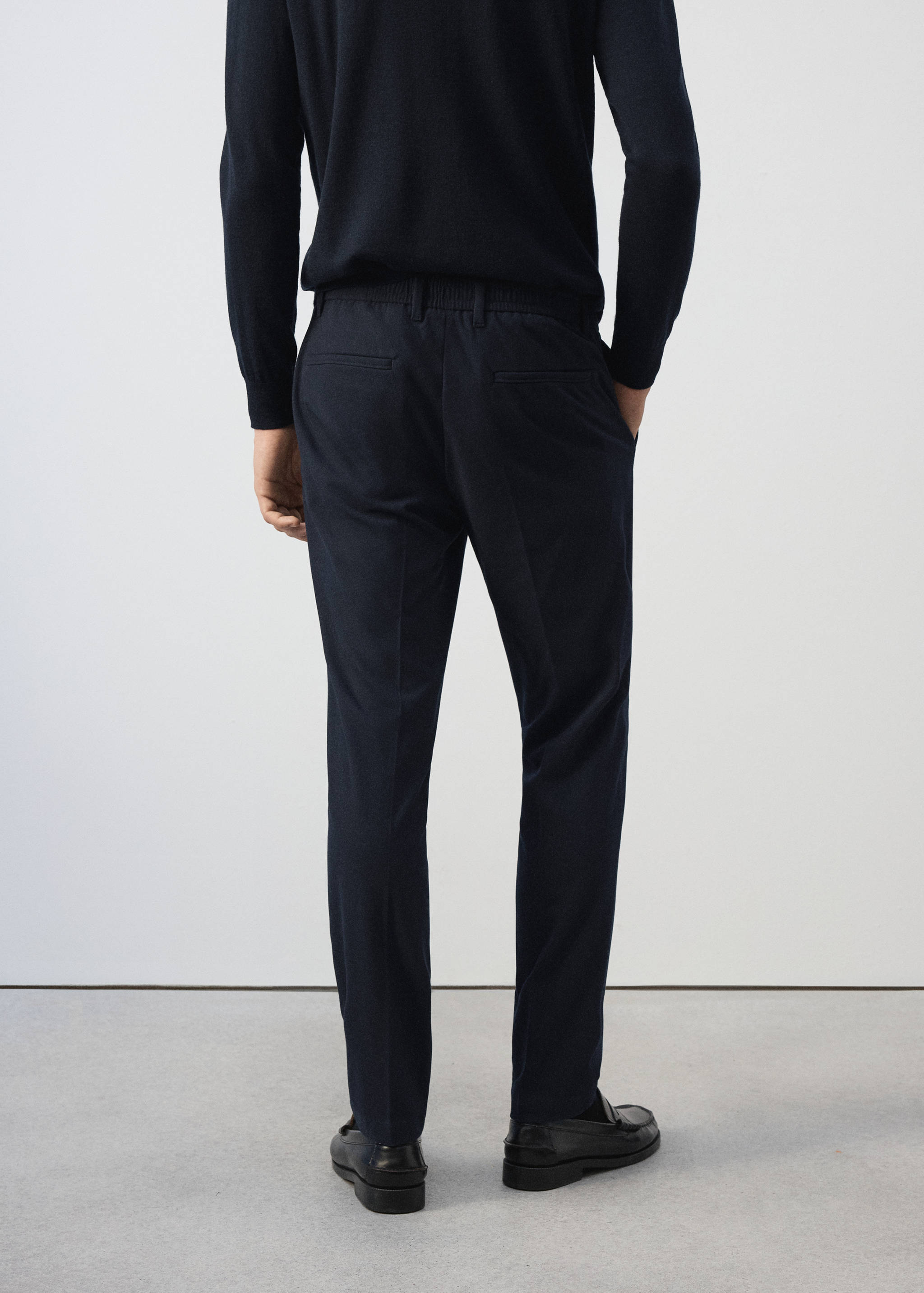 Navy blue trousers from the back, featuring a tailored fit and back pockets.
