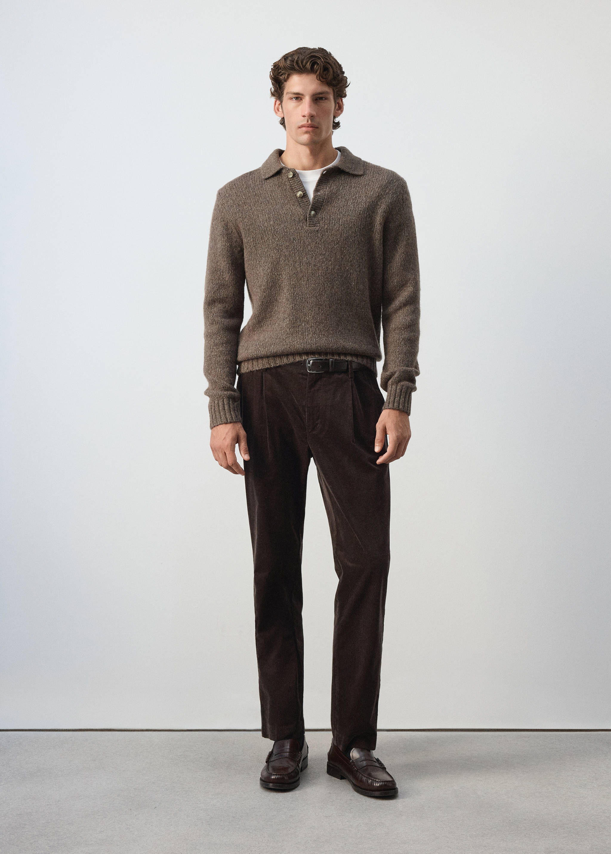 Pantalones de pana en marrón oscuro con pinzas, combinados con un polo de punto marrón.