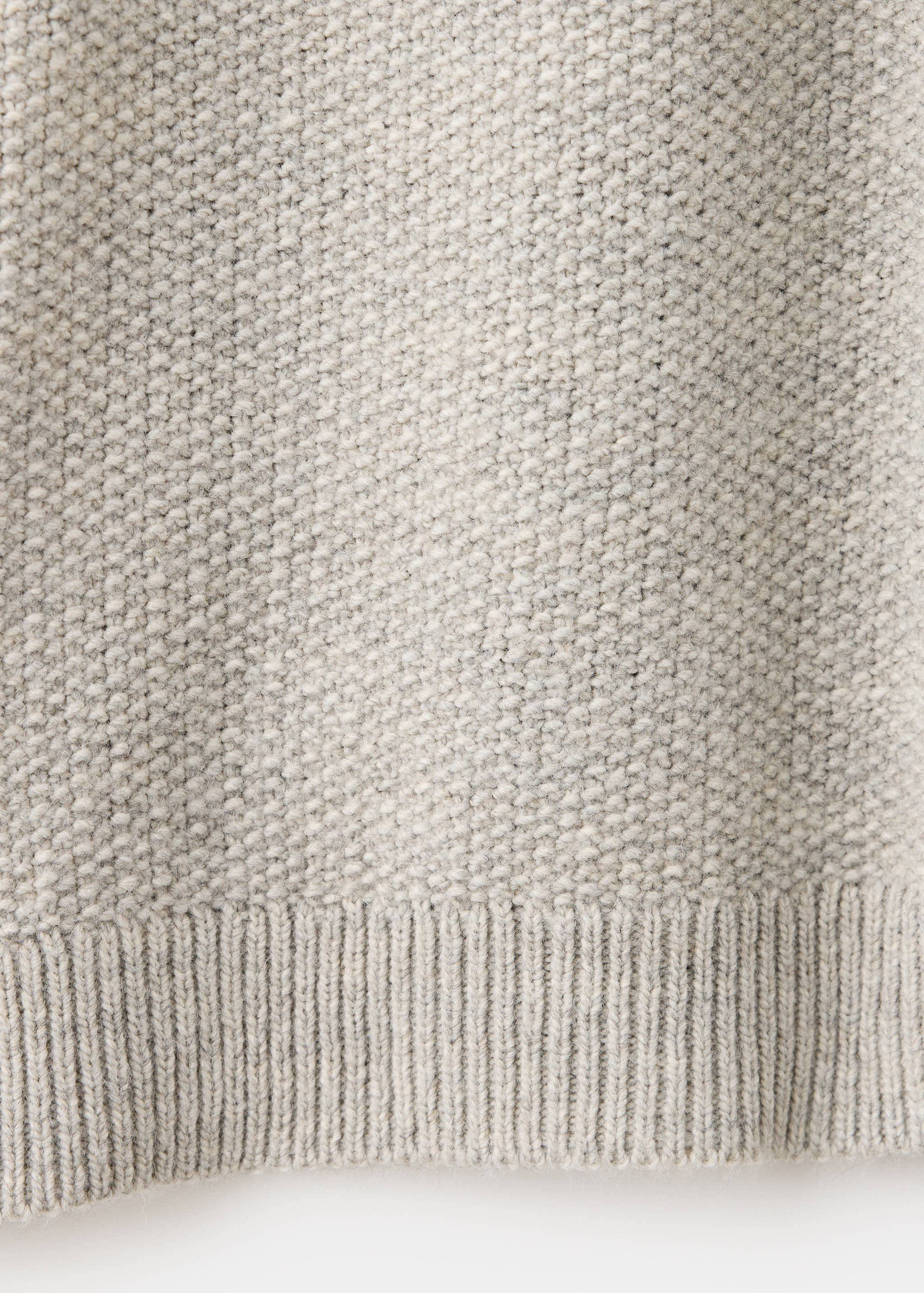 Close-up of the textured knit and ribbed hem on a grey jersey.