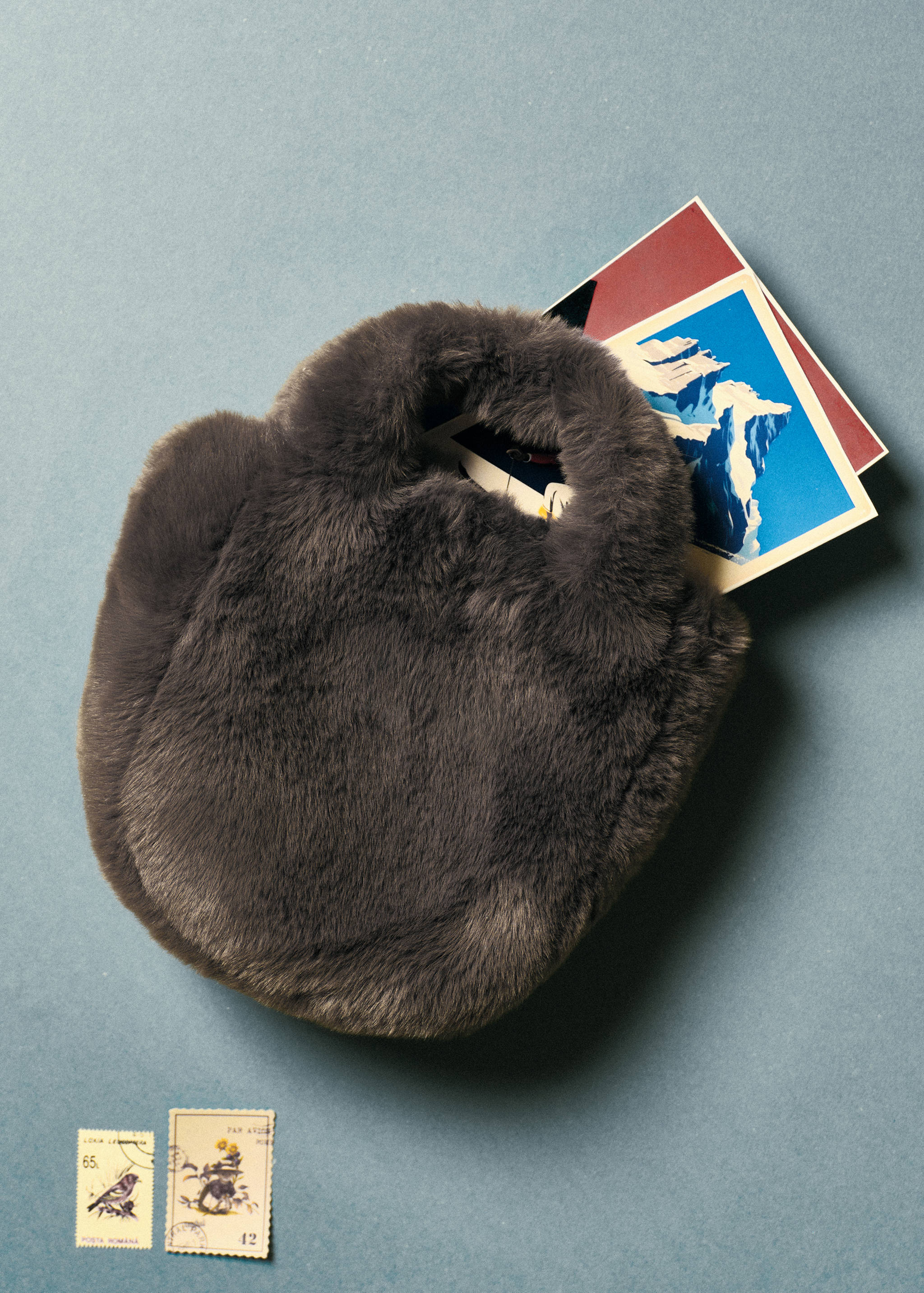 Dark grey faux-fur mini bag with postcards tucked inside.