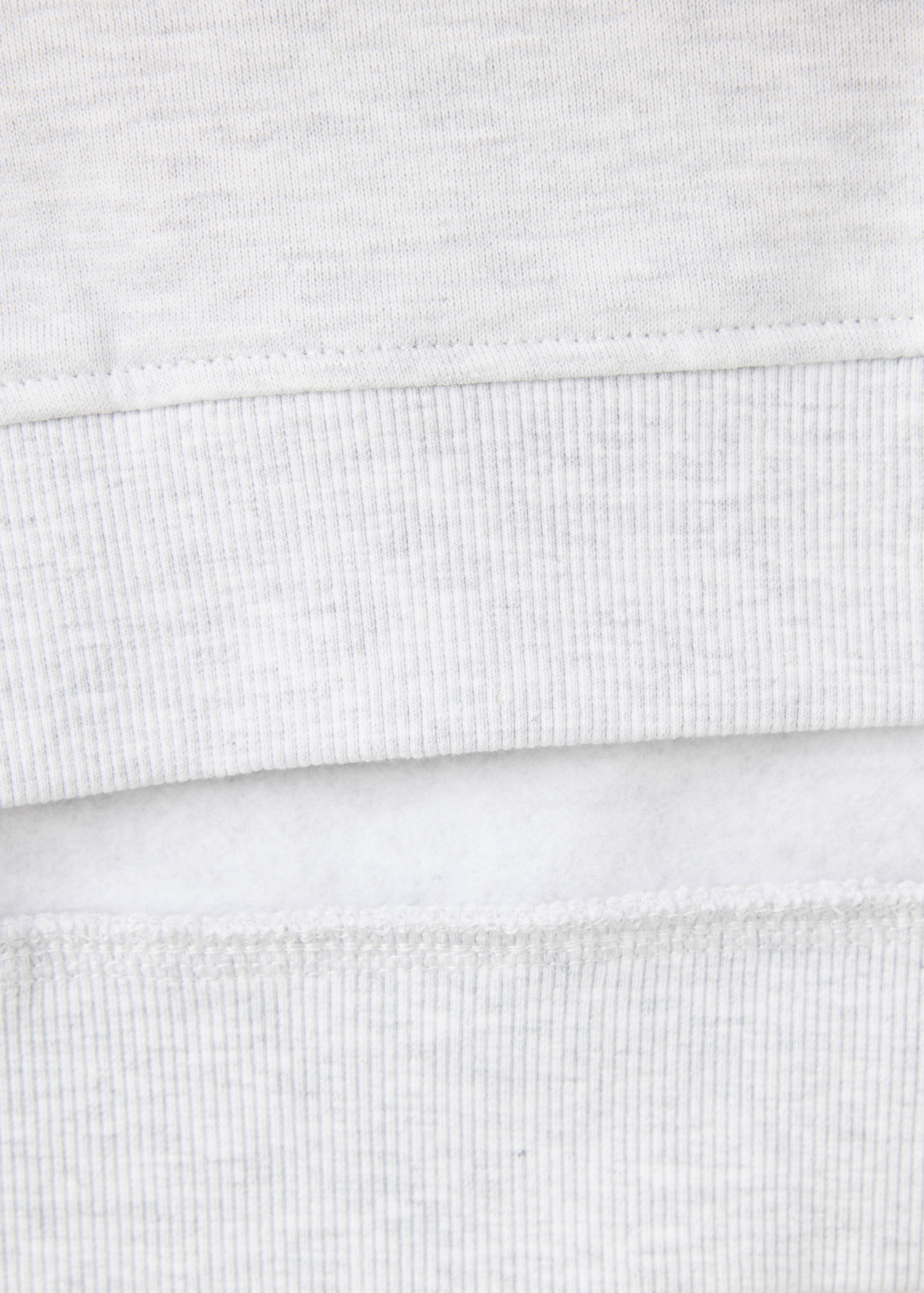 Close-up of the grey sweatshirt's fabric texture and ribbed hem.