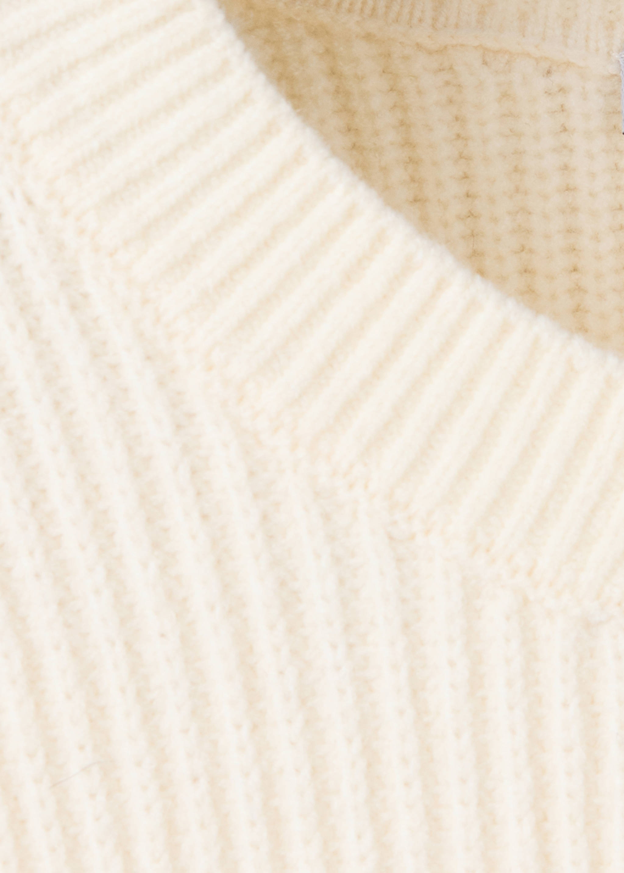 Close-up of a cream jumper showing the ribbed crew neckline.