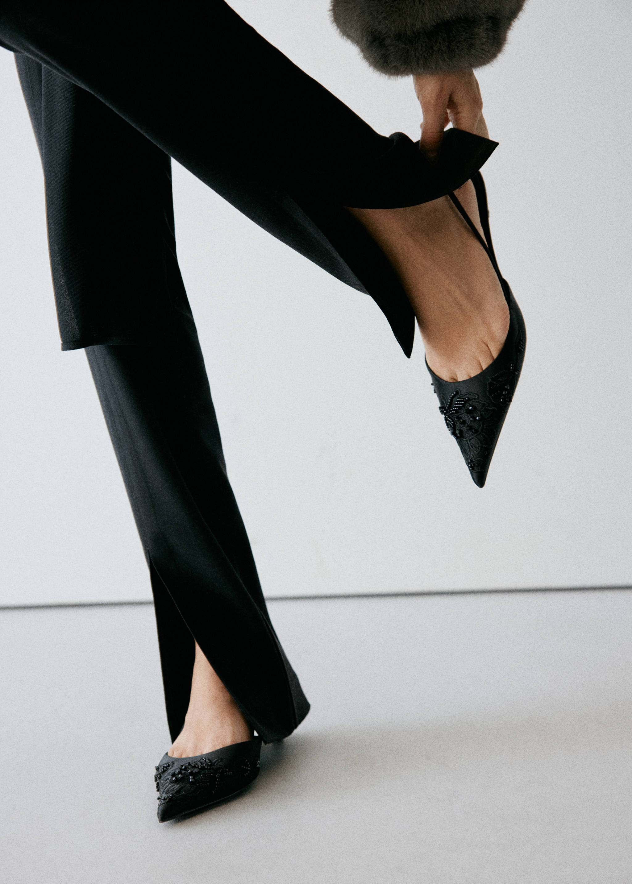 Black beaded pointed-toe slingback shoes worn with slit trousers.