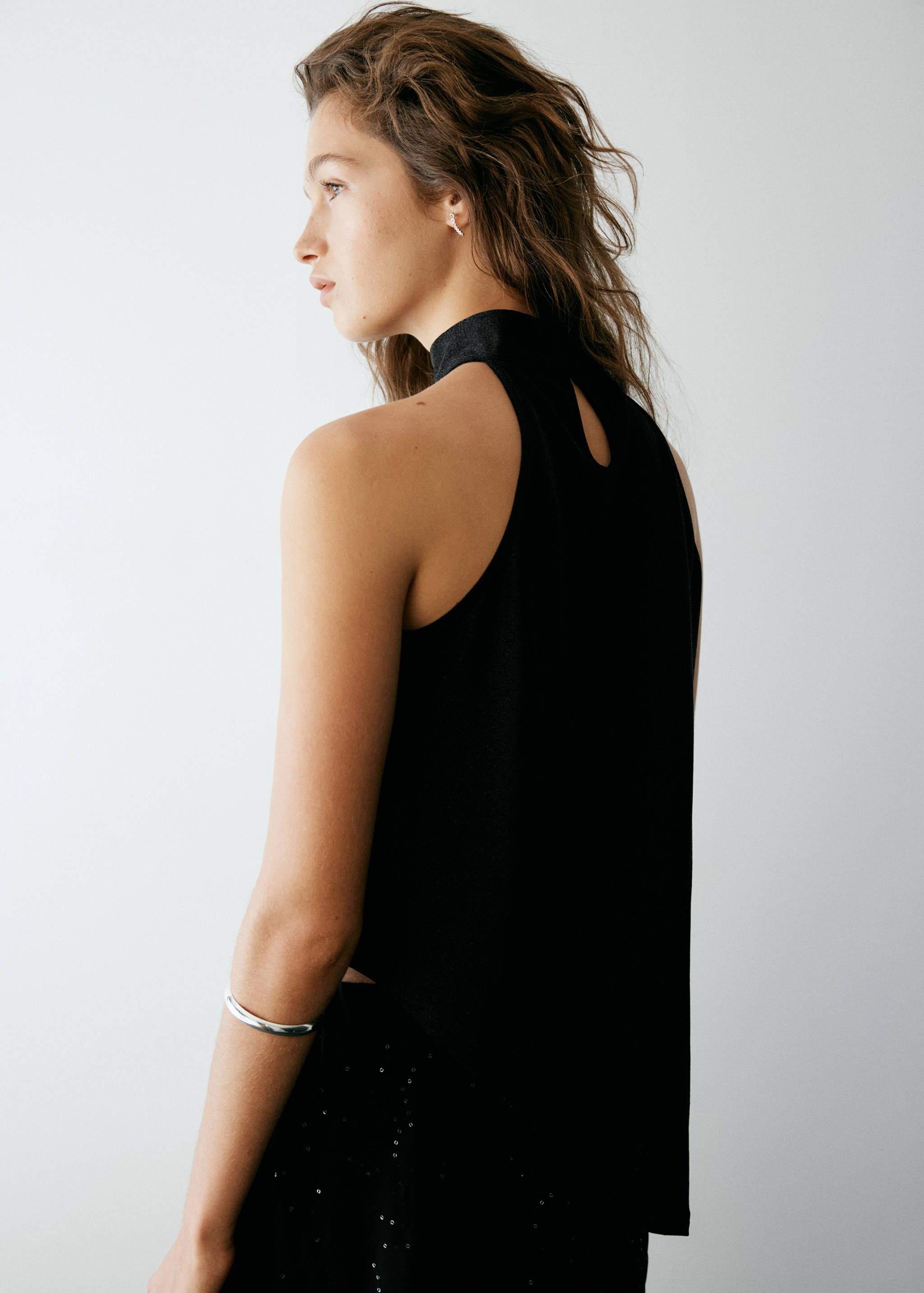 Black sleeveless top with a high collar and back keyhole, shown from the back view.