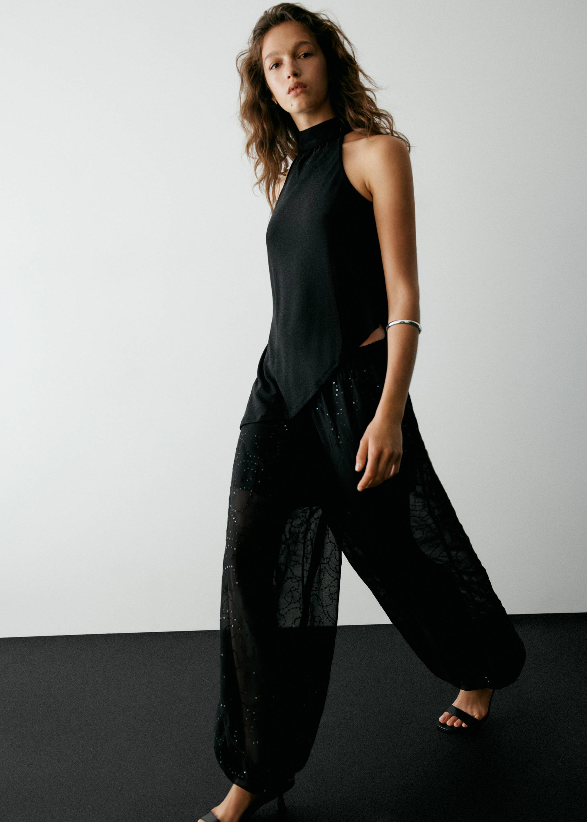Black halter-neck top with an asymmetrical handkerchief hem and mock neck.