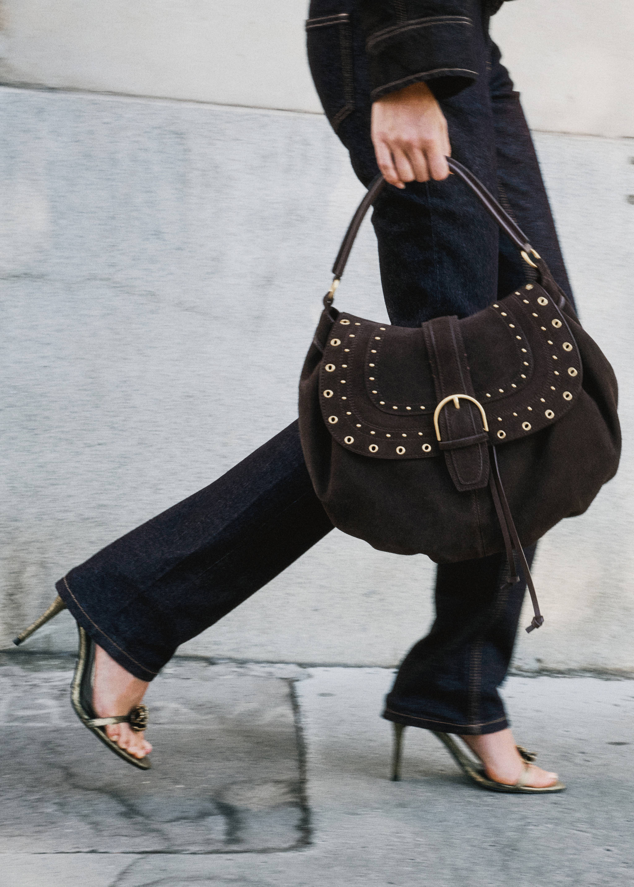 Dark brown suede shoulder bag with metallic eyelets and buckle closure.