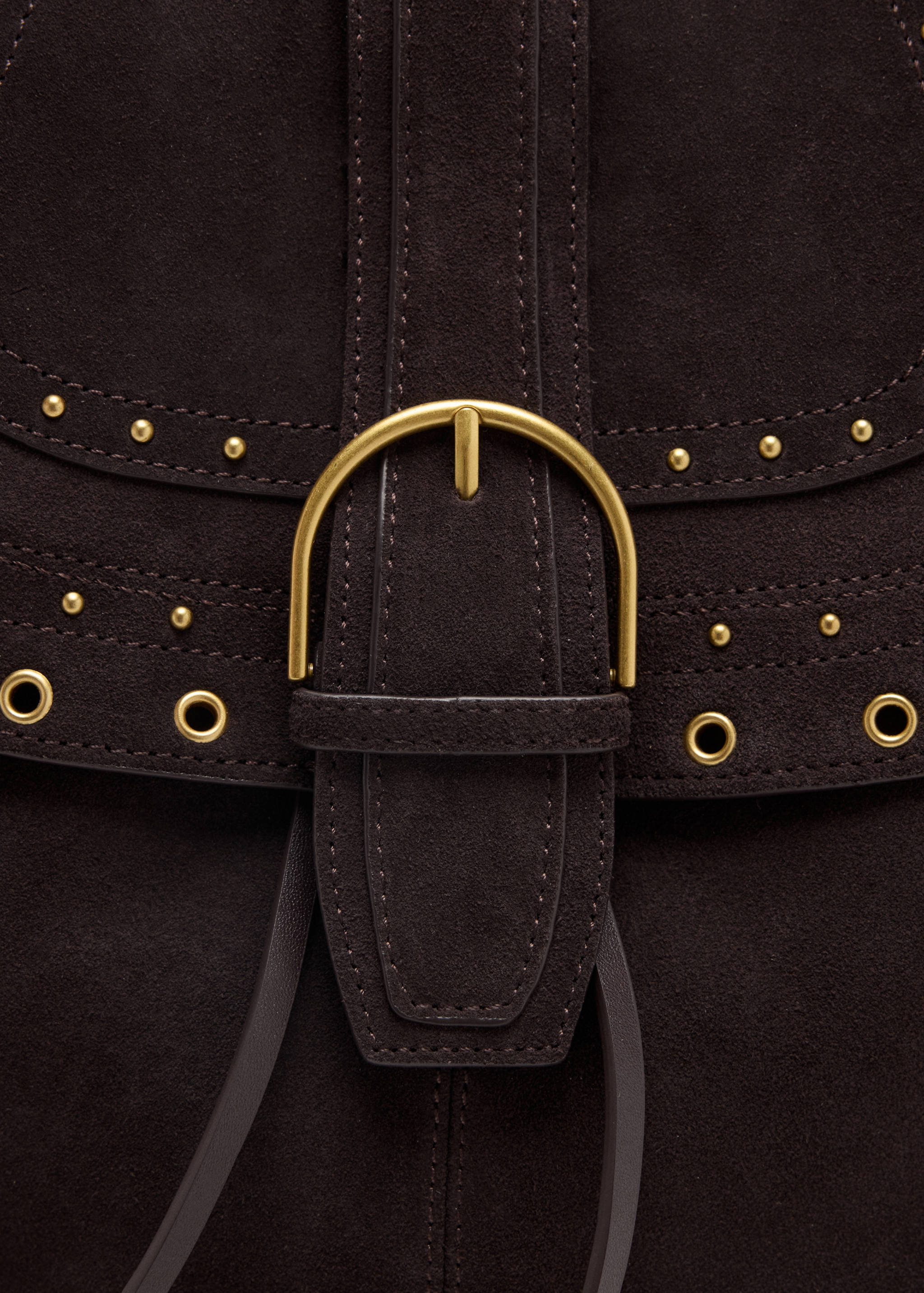 Close-up of a dark brown suede shoulder bag with a gold buckle and stud details.