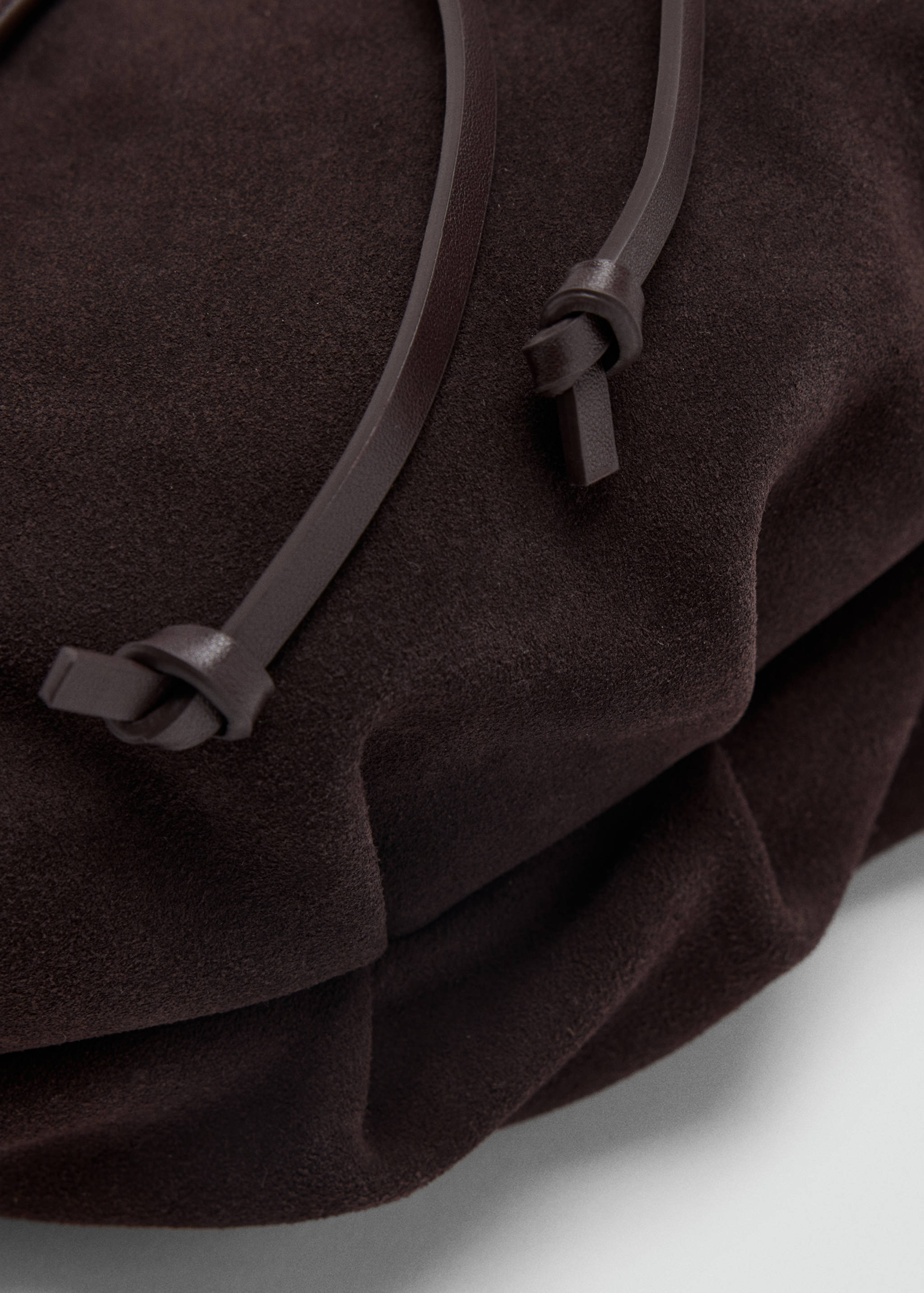 Dark brown suede shoulder bag detail, showing leather drawstrings.