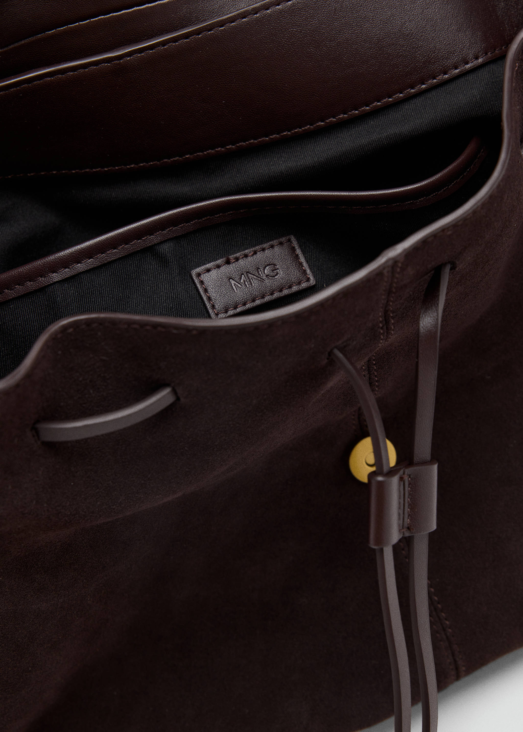 Close-up of the interior detail and drawstring closure of a dark brown suede shoulder bag.