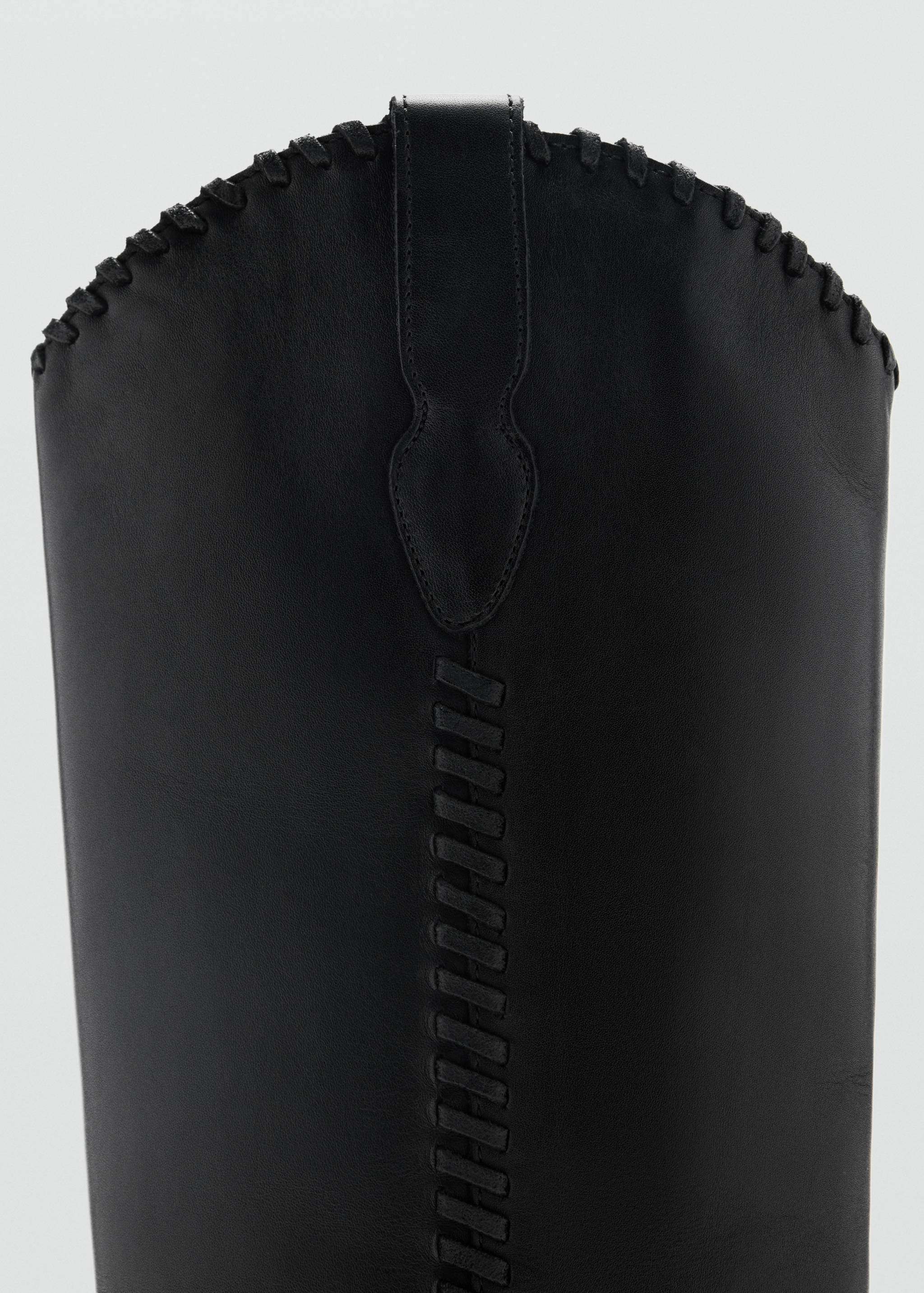 Close-up of black boot shaft with whipstitch detail.