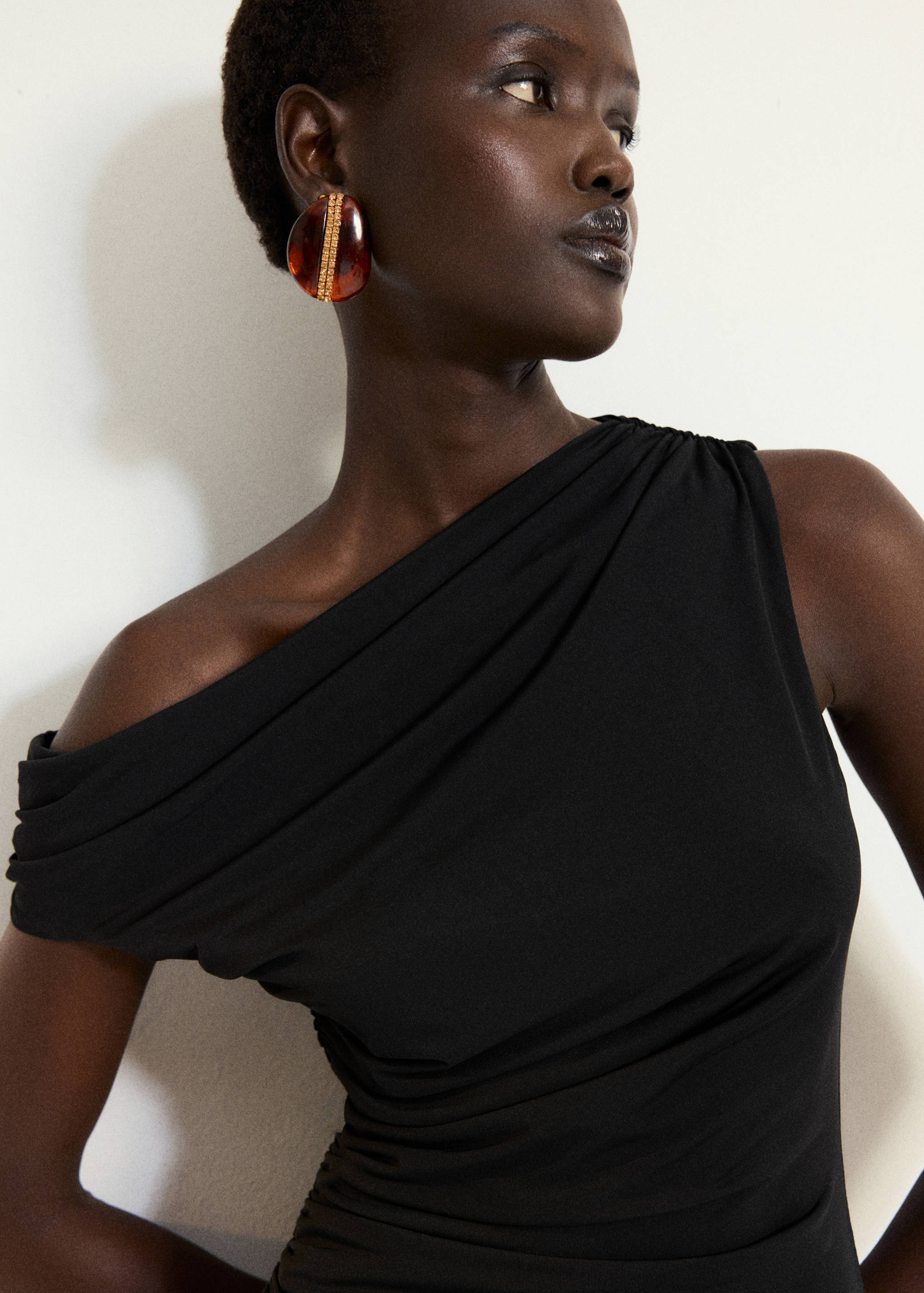 Black one-shoulder dress with draped bodice and gathered ruching.