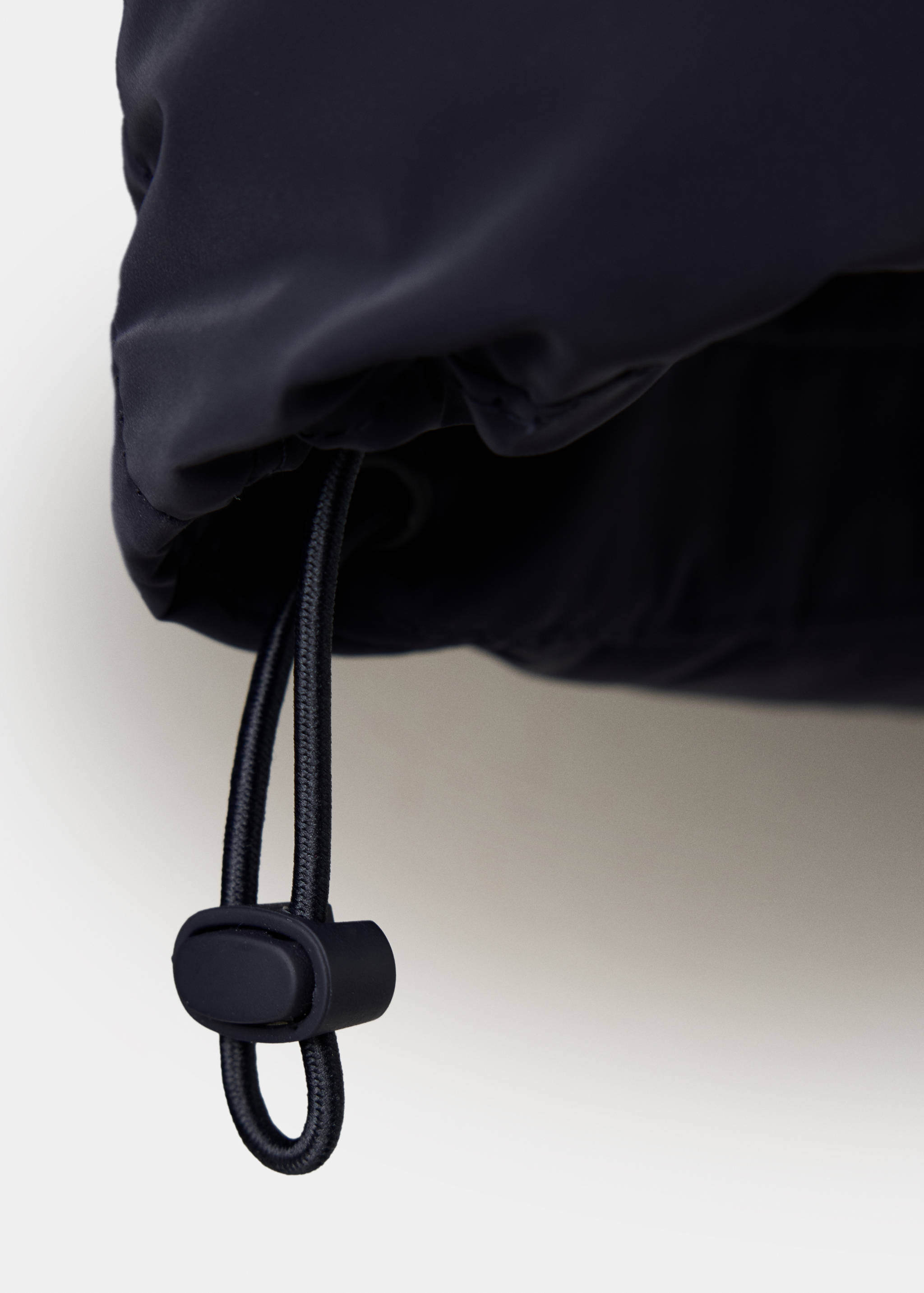 Close-up of the adjustable drawstring hem on a dark navy blue anorak.