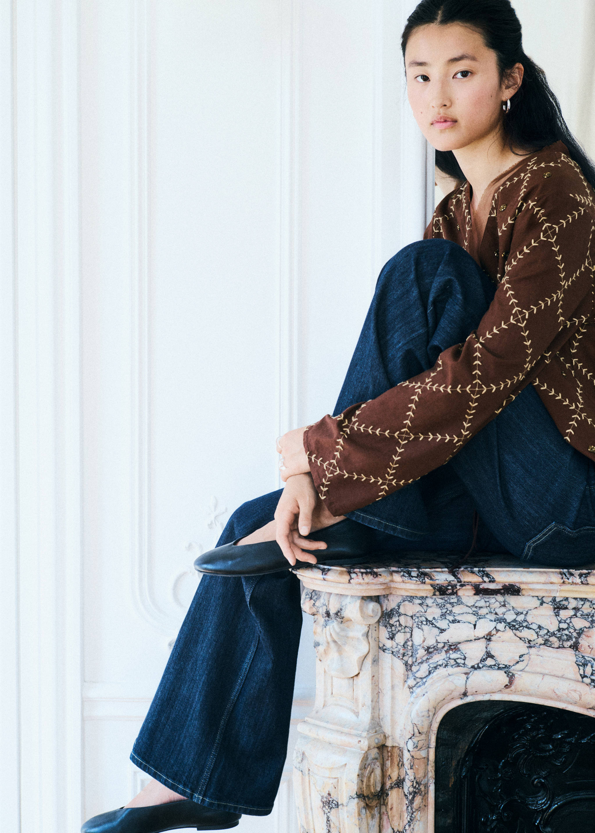 Brown embroidered top with dark blue denim trousers, back view.