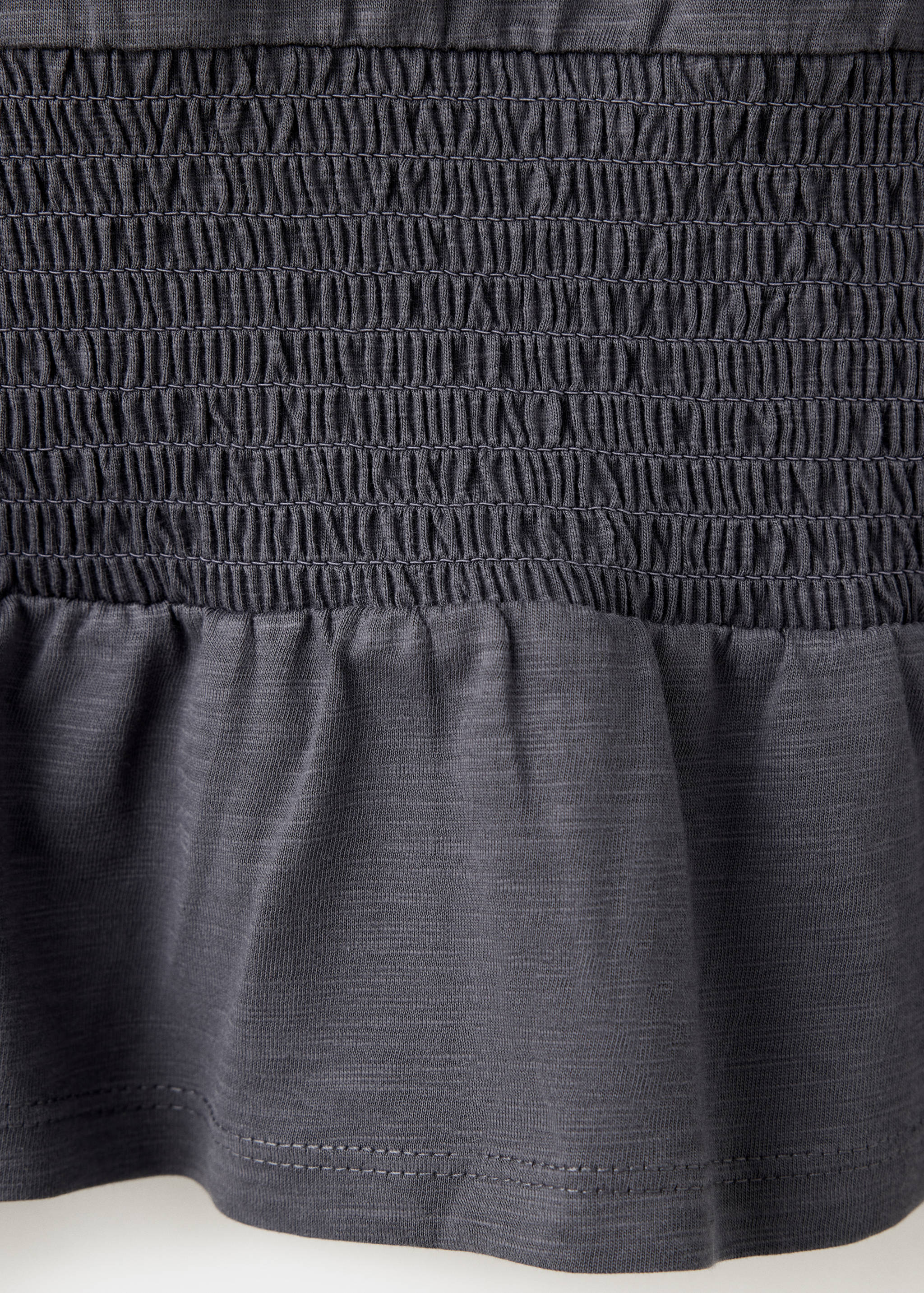 Primer plano del detalle de tejido nido de abeja en una camiseta gris oscuro.