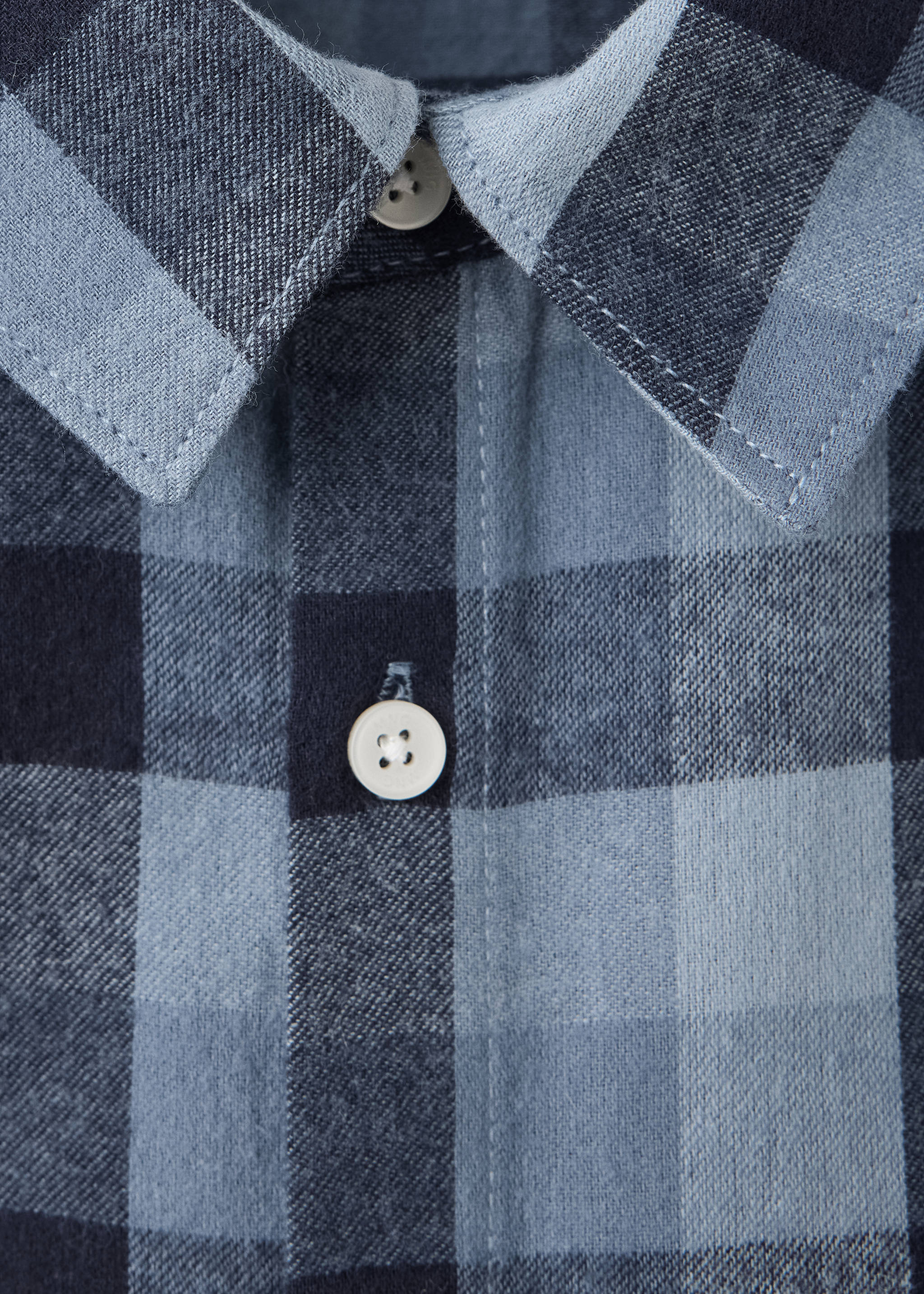 Close-up of a blue and navy checked shirt collar and button placket.