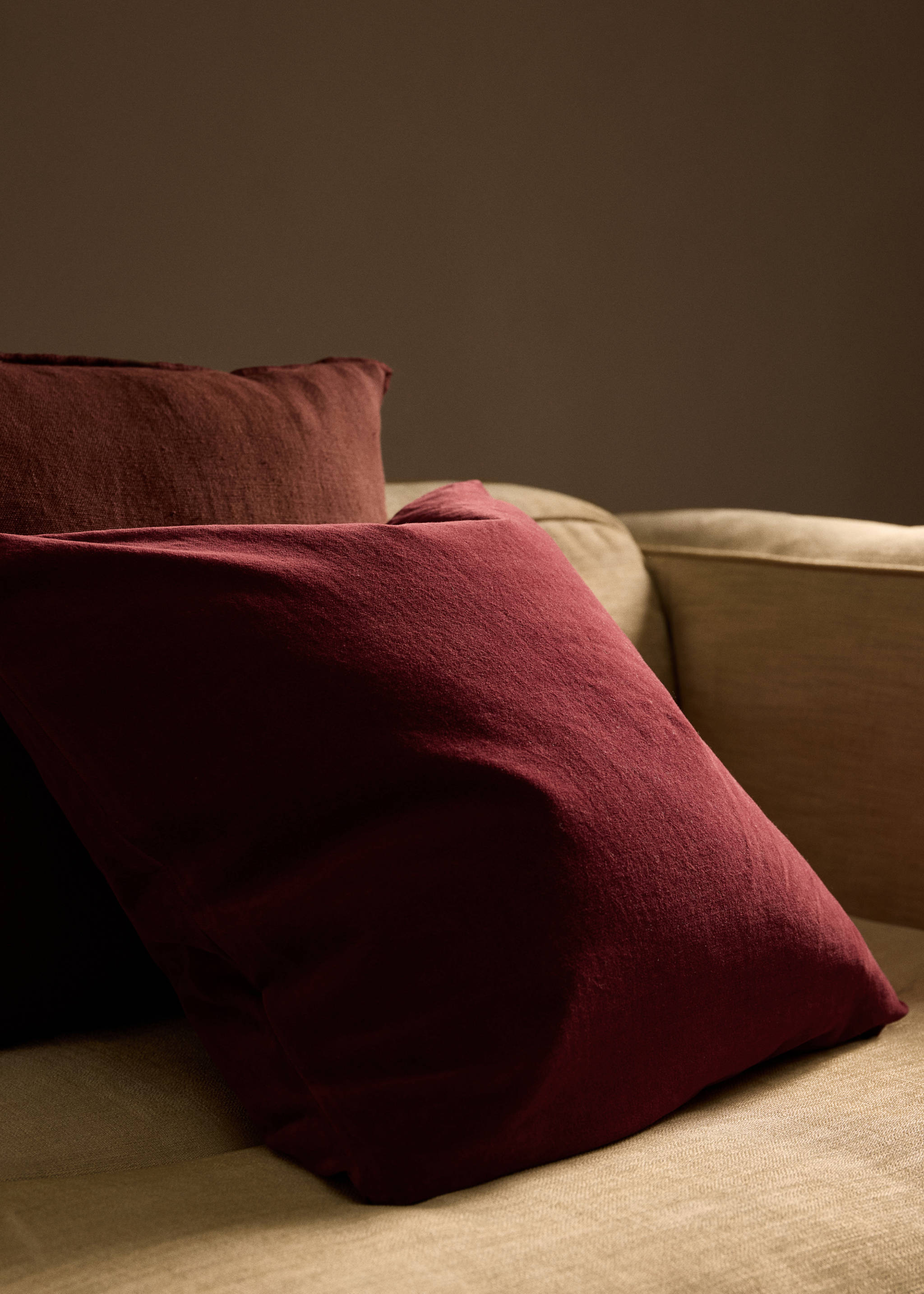 Dark red cushion cover on a beige sofa.