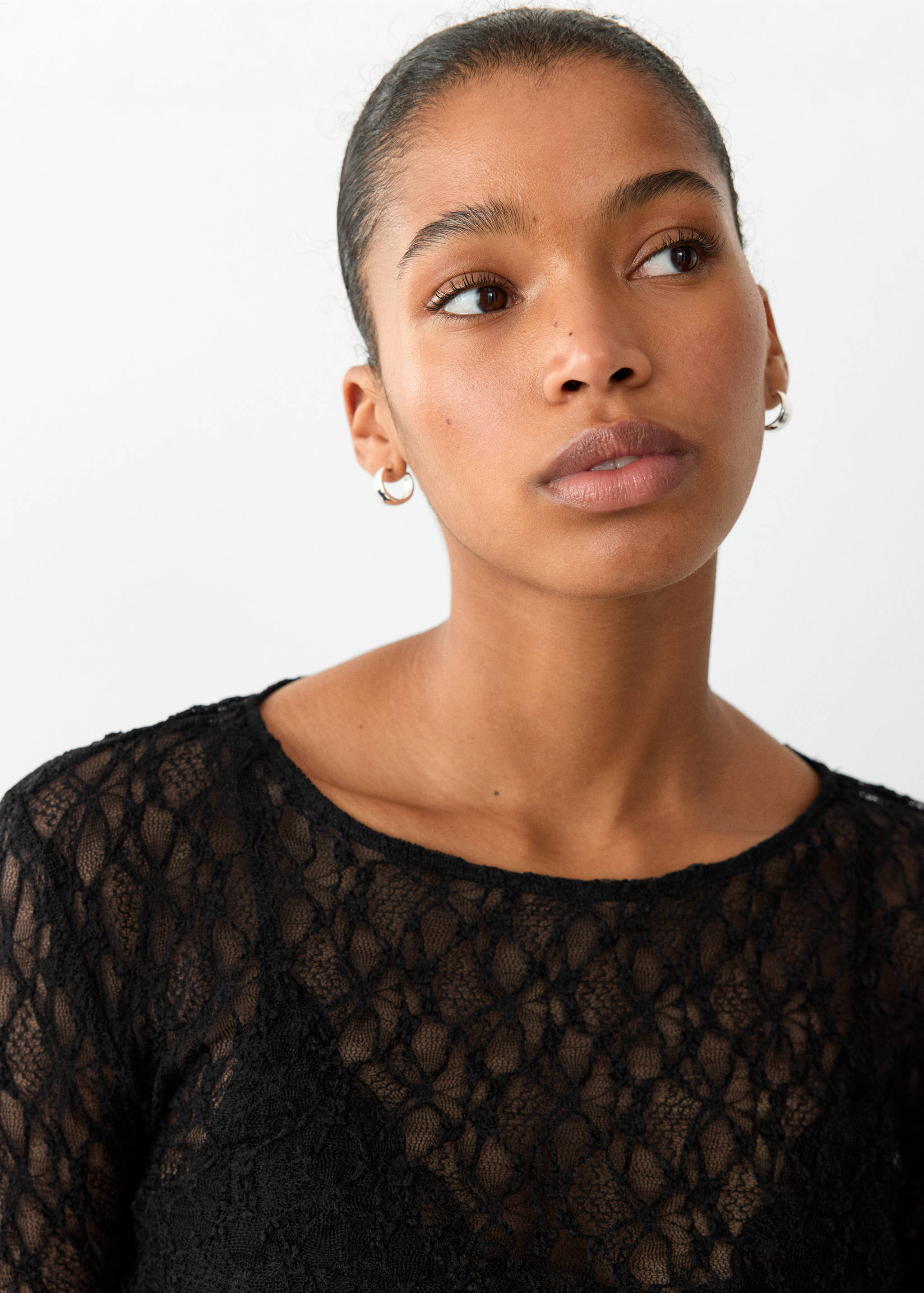Close-up of a model wearing a black lace round-neck T-shirt.