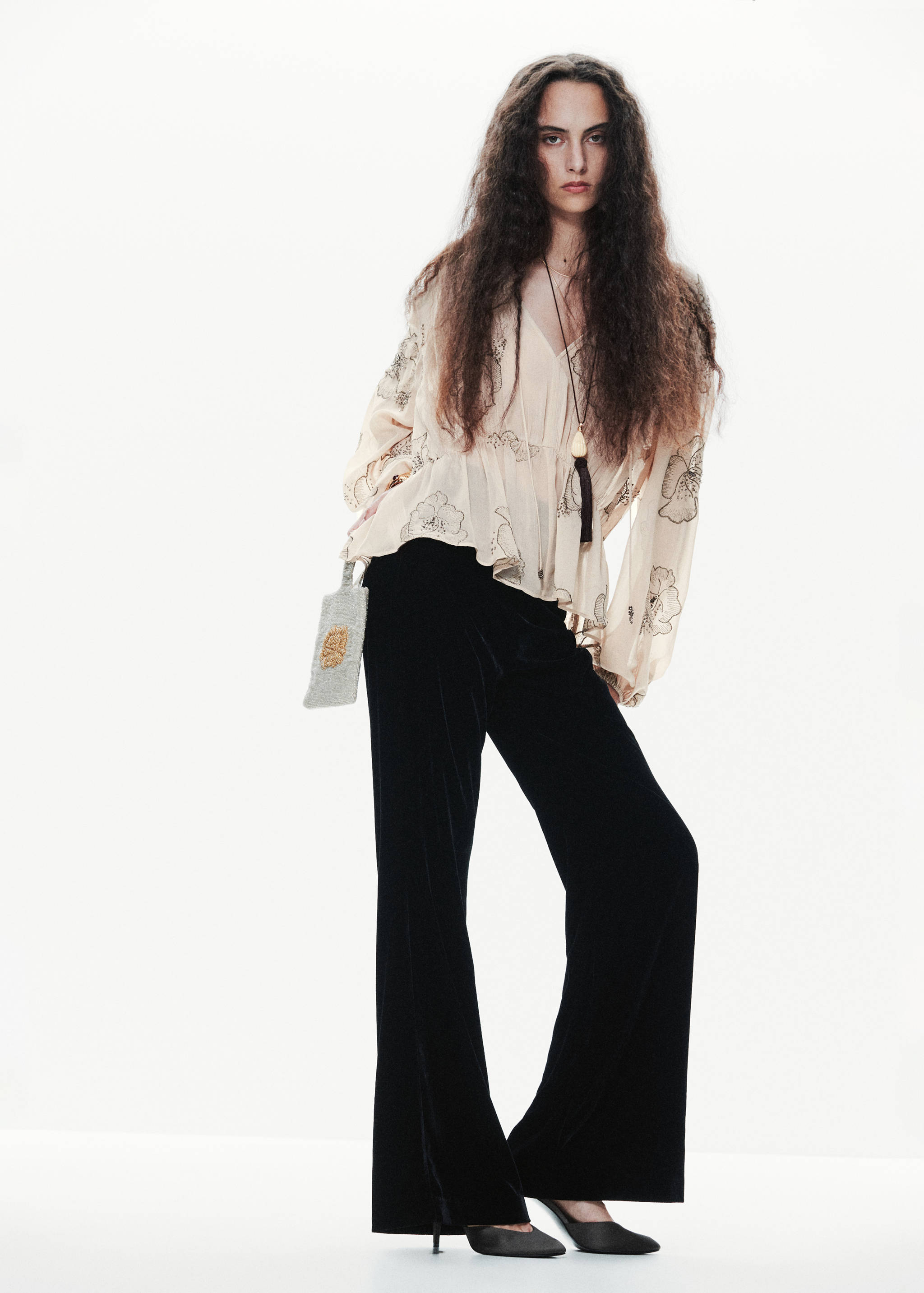Blusa de manga larga con estampado floral en color crudo, combinada con pantalones negros de terciopelo.