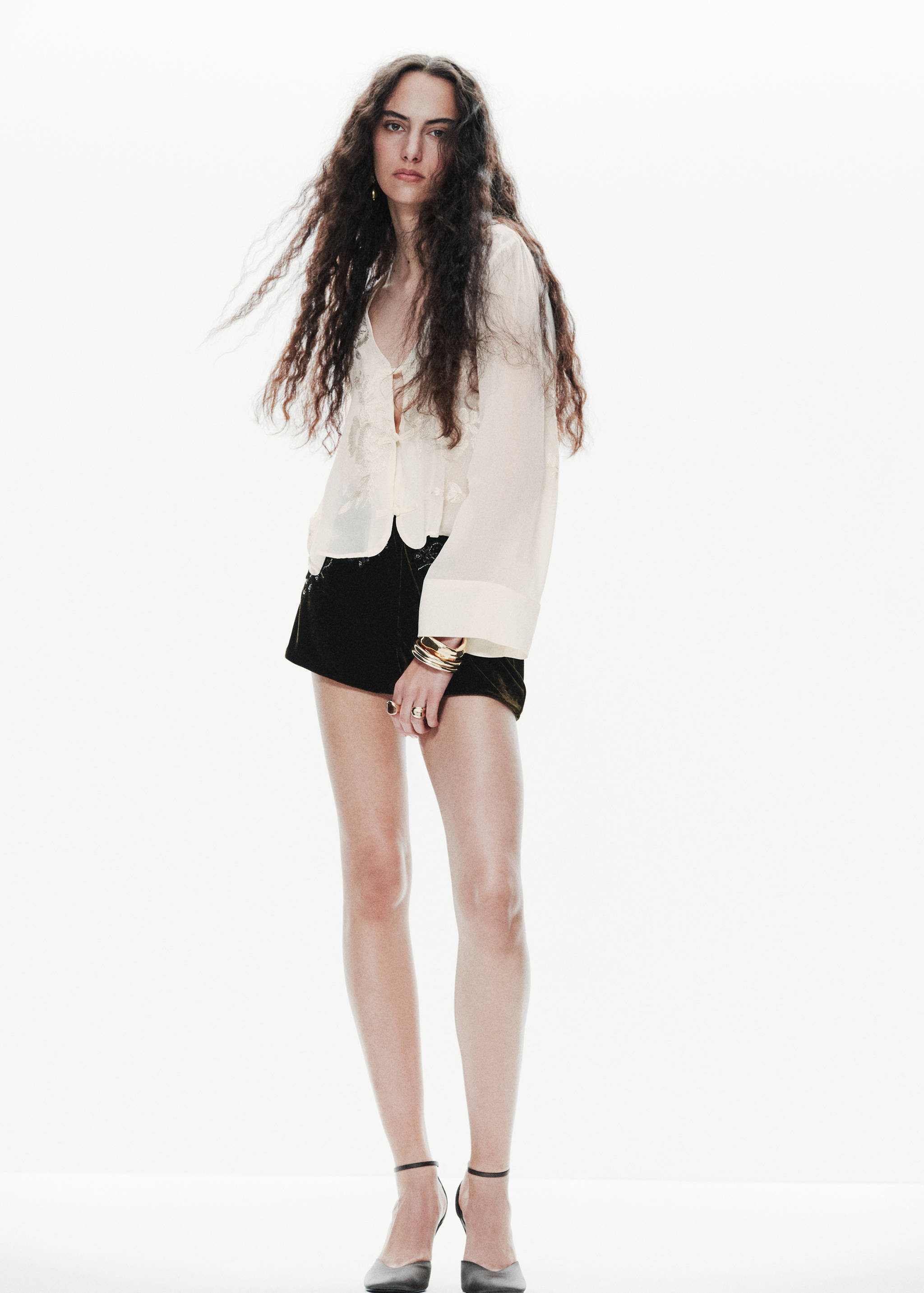 Blusa blanca rota con bordado floral y manga larga acampanada.