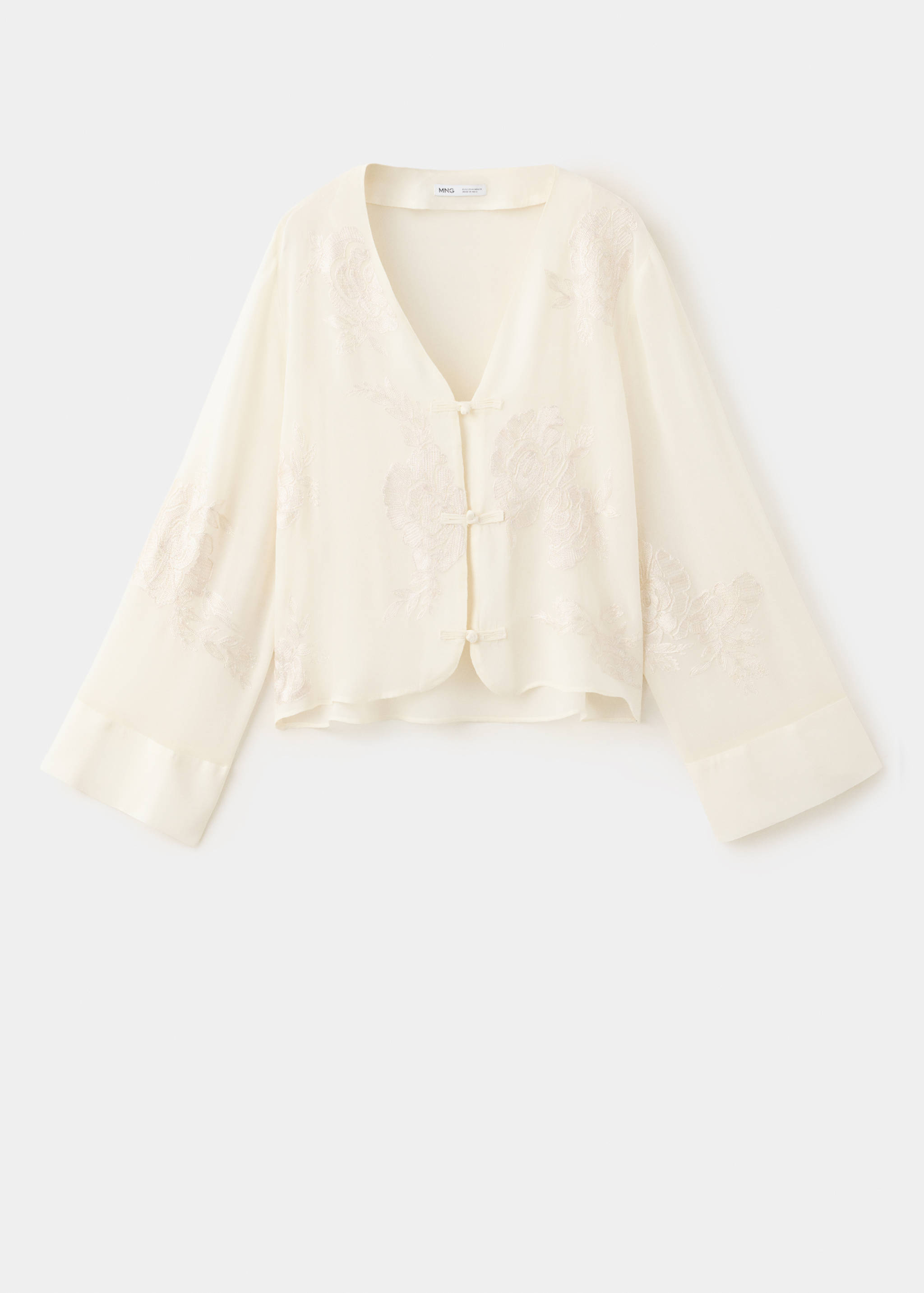 Blusa color crema con cuello de pico, manga larga ancha y cierres de gancho delanteros.