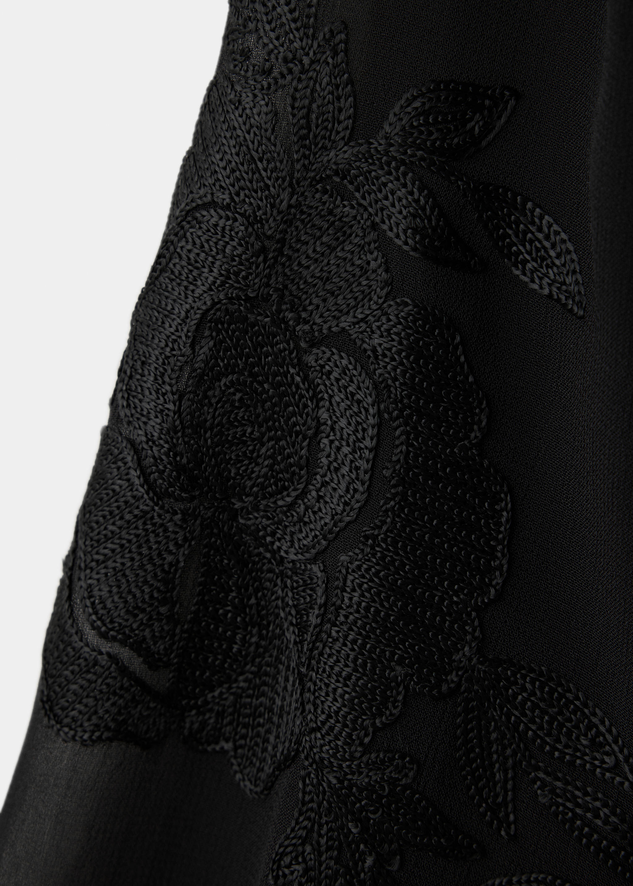 Detalle del tejido de la blusa negra con motivos florales bordados al tono.