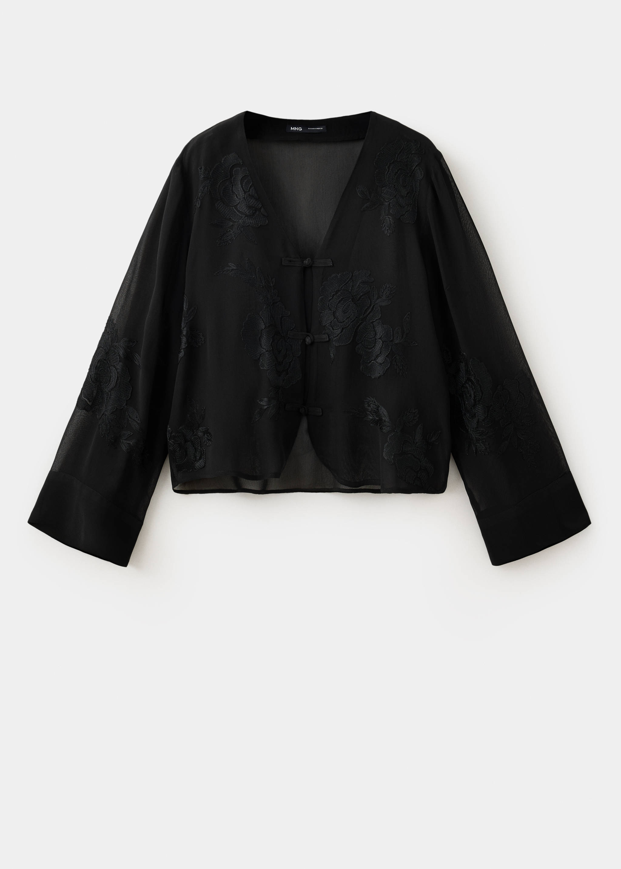 Blusa negra transparente con bordados, cuello en V y cierres de gancho.
