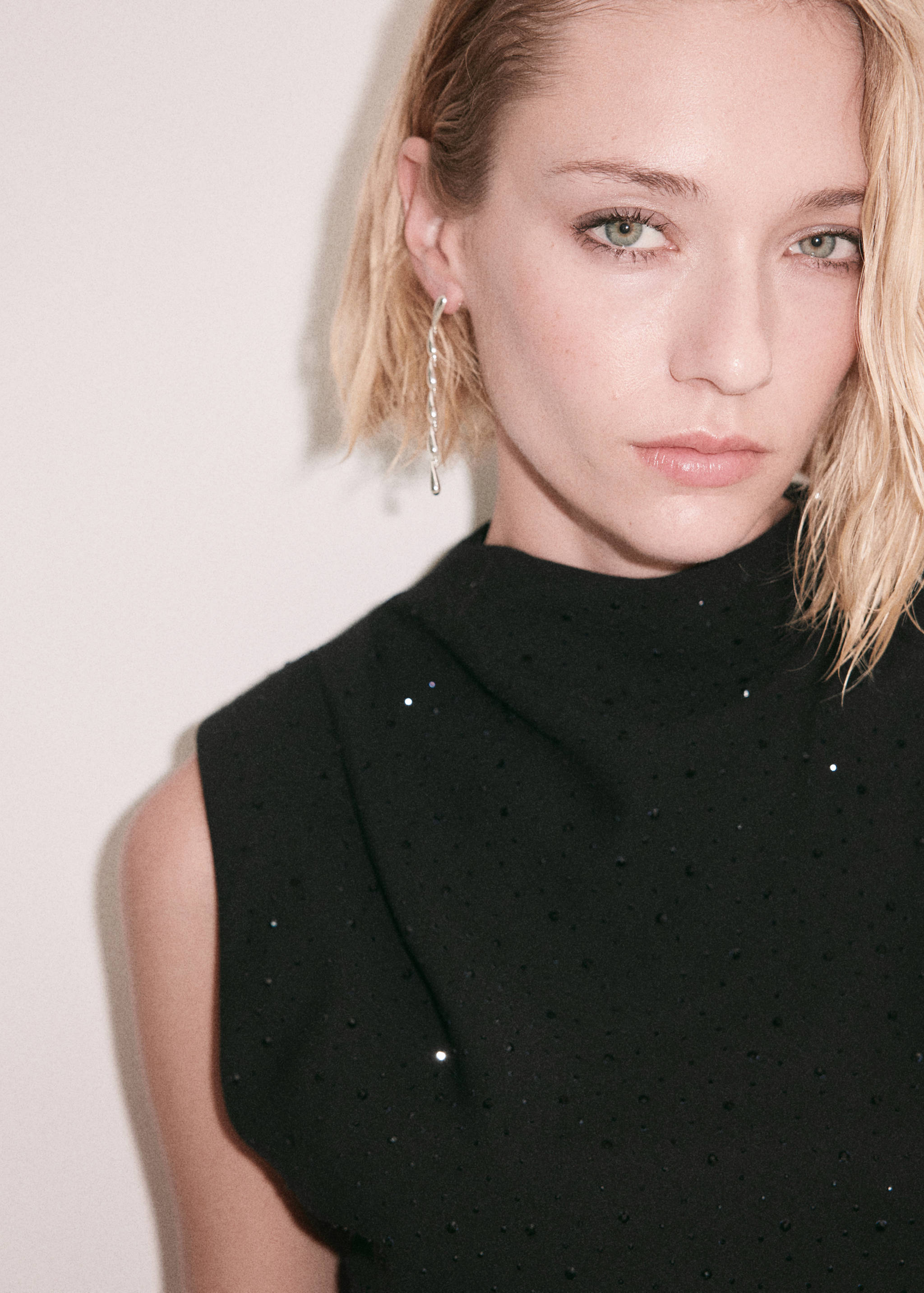 Close-up of a black sleeveless rhinestone blouse on a model.