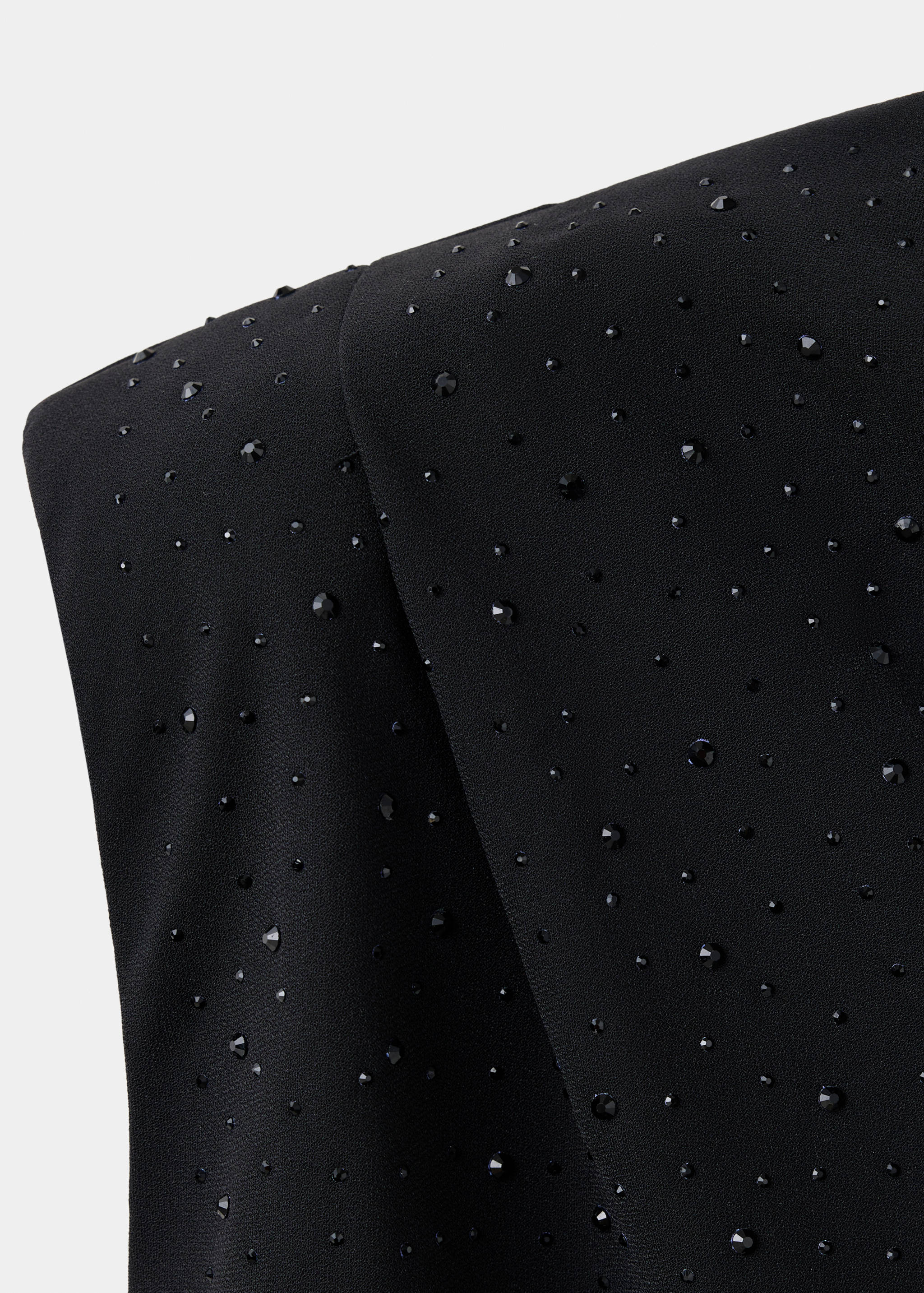 Close-up of a black blouse embellished with faceted black rhinestones.