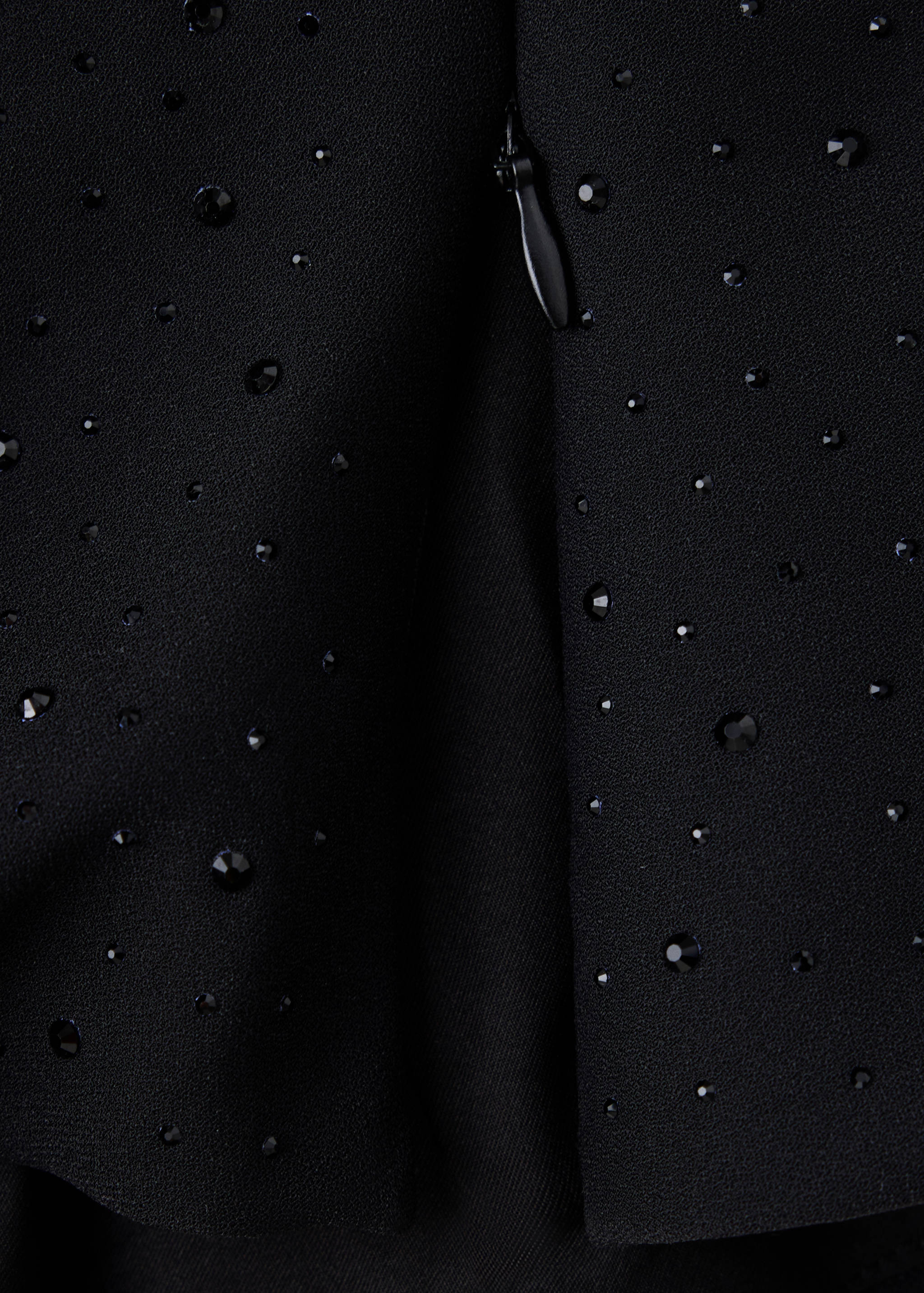 Close-up of a black blouse fabric with rhinestone embellishments.