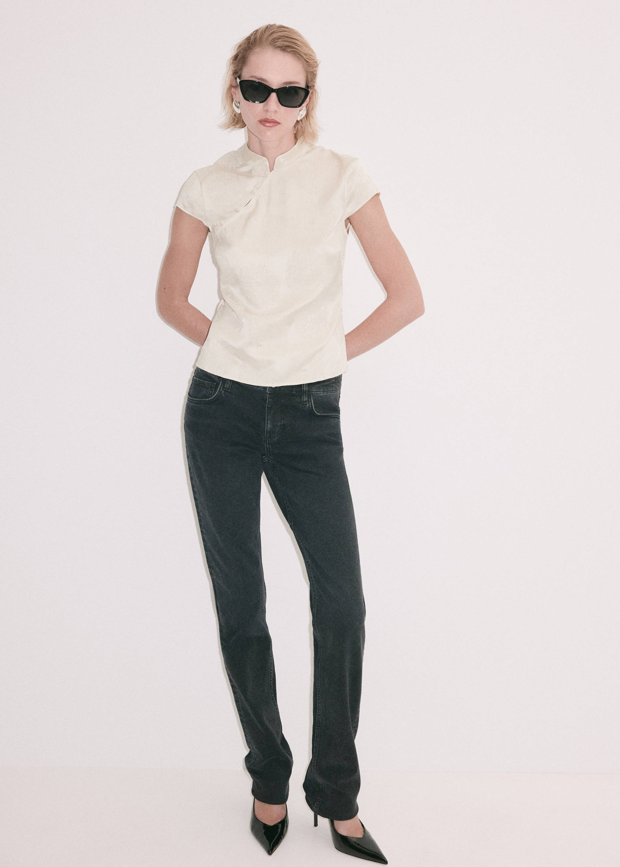Blusa corta de cuello mao en color crudo combinada con vaqueros oscuros.