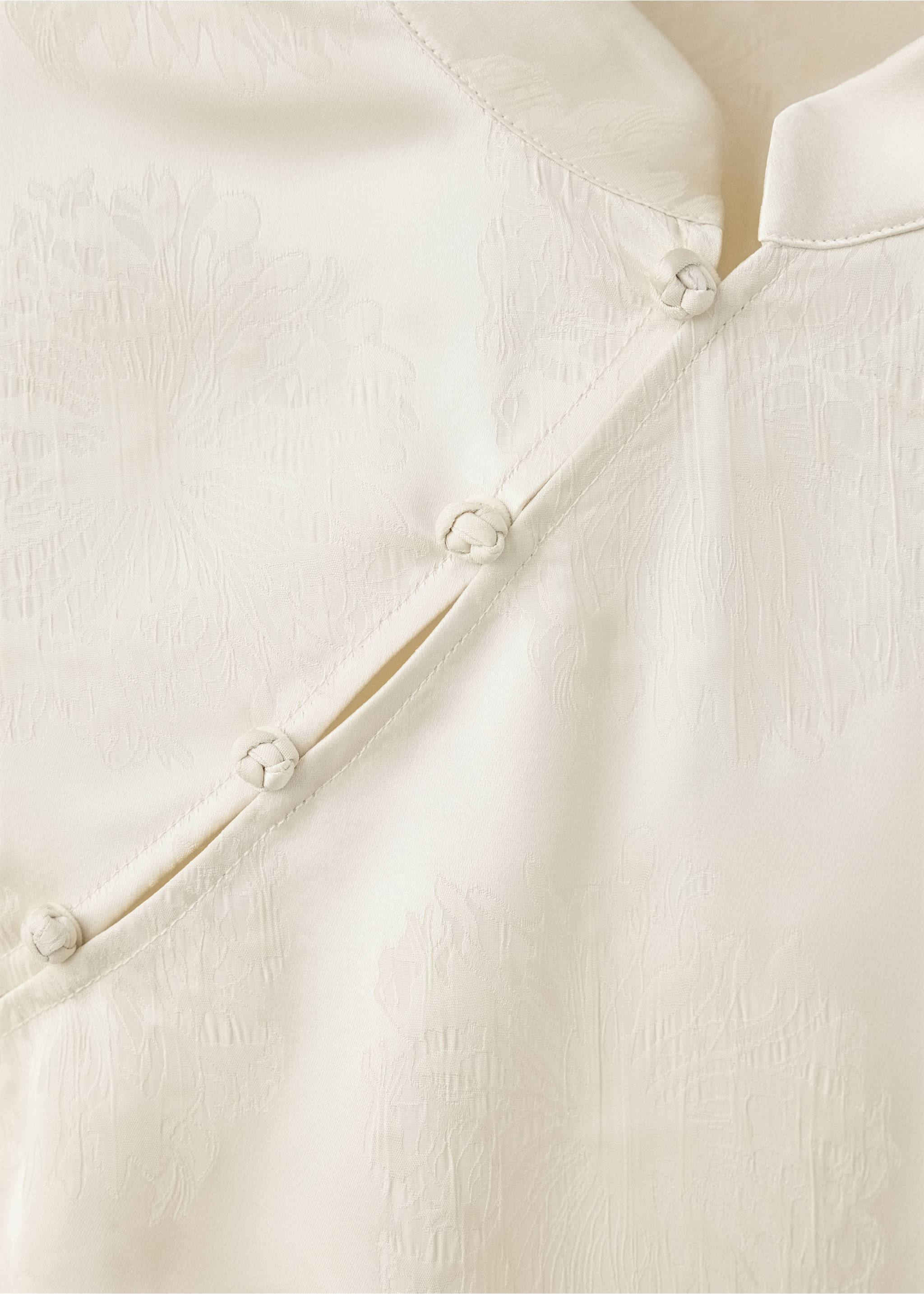 Detalle de blusa jacquard en crudo con cierre de botones y nudo diagonal., Crudo. Ref: 37019128-00.