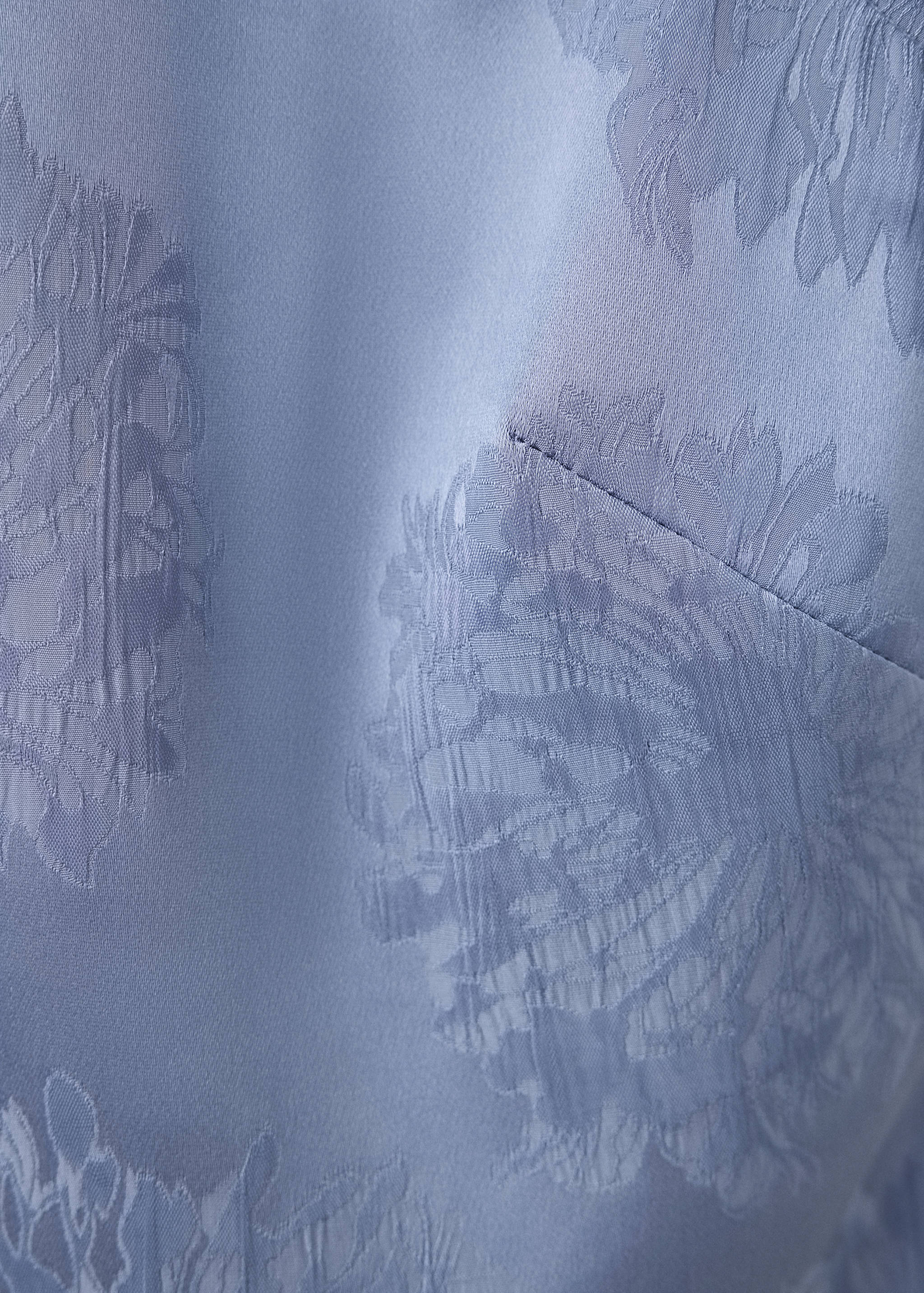 Primer plano del tejido de una blusa azul claro con motivo de jacquard floral.