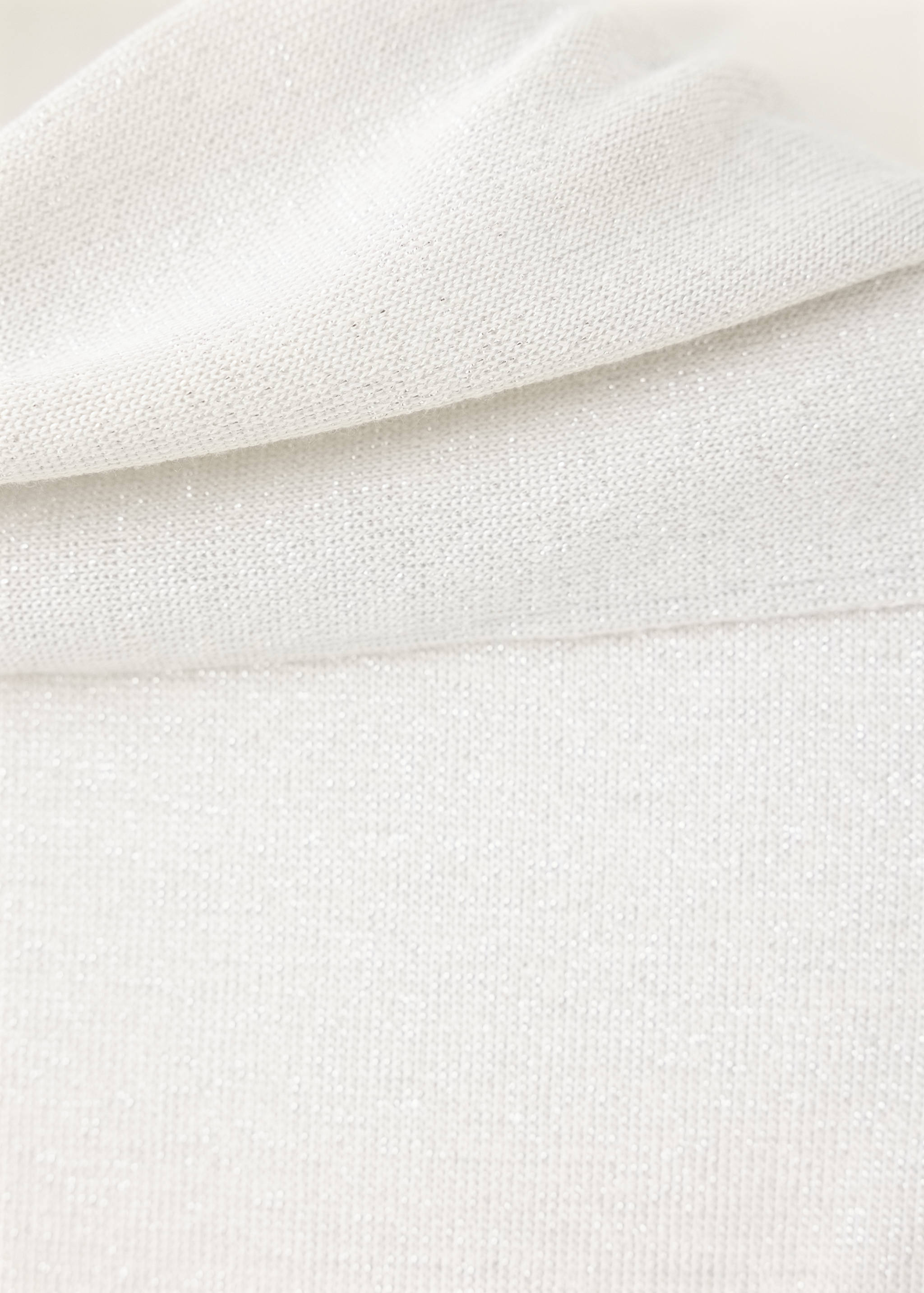 Close-up of a white knitted top showing the textured fabric and collar.
