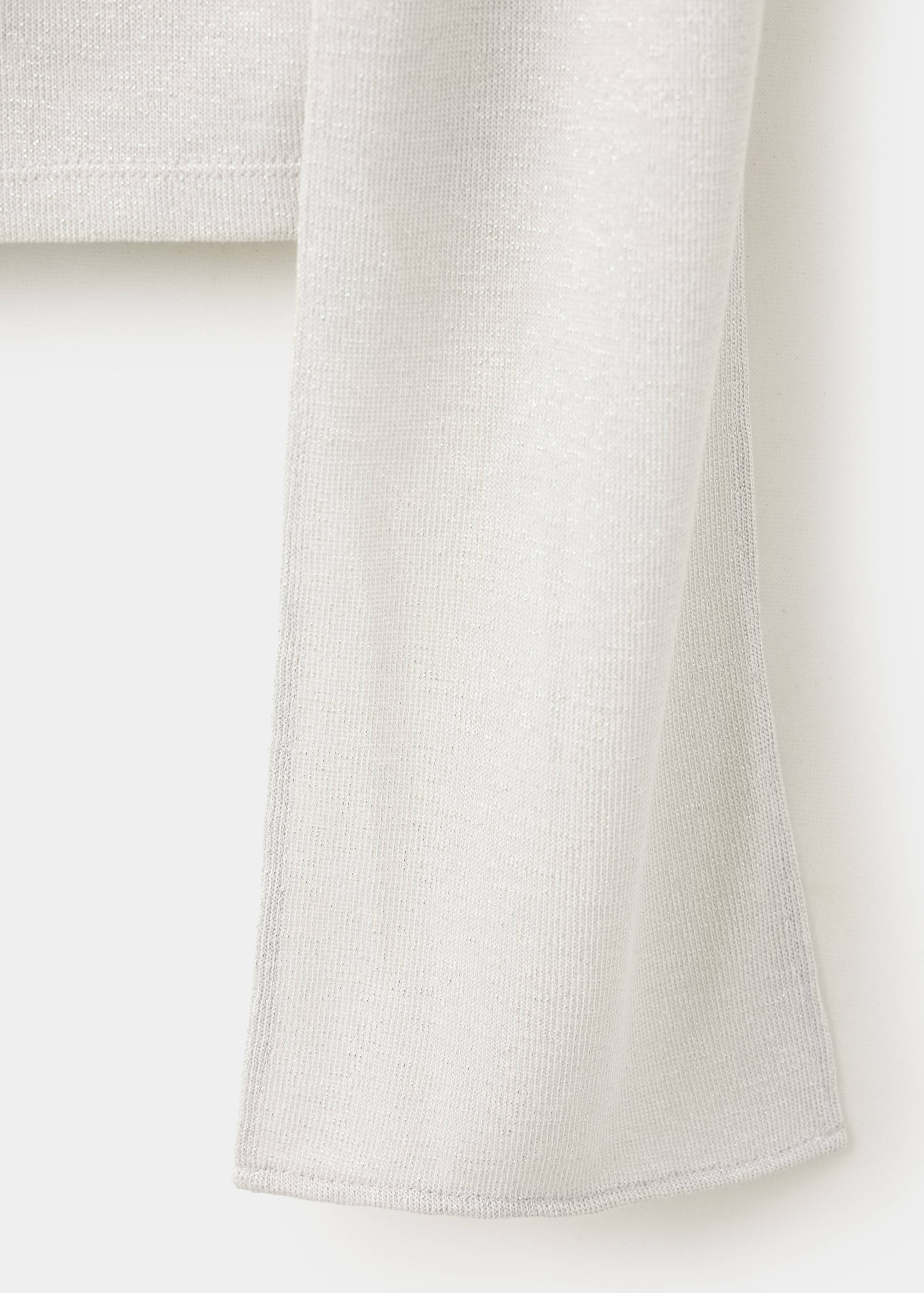 Close-up of the fine metallic knit fabric of a light grey top.
