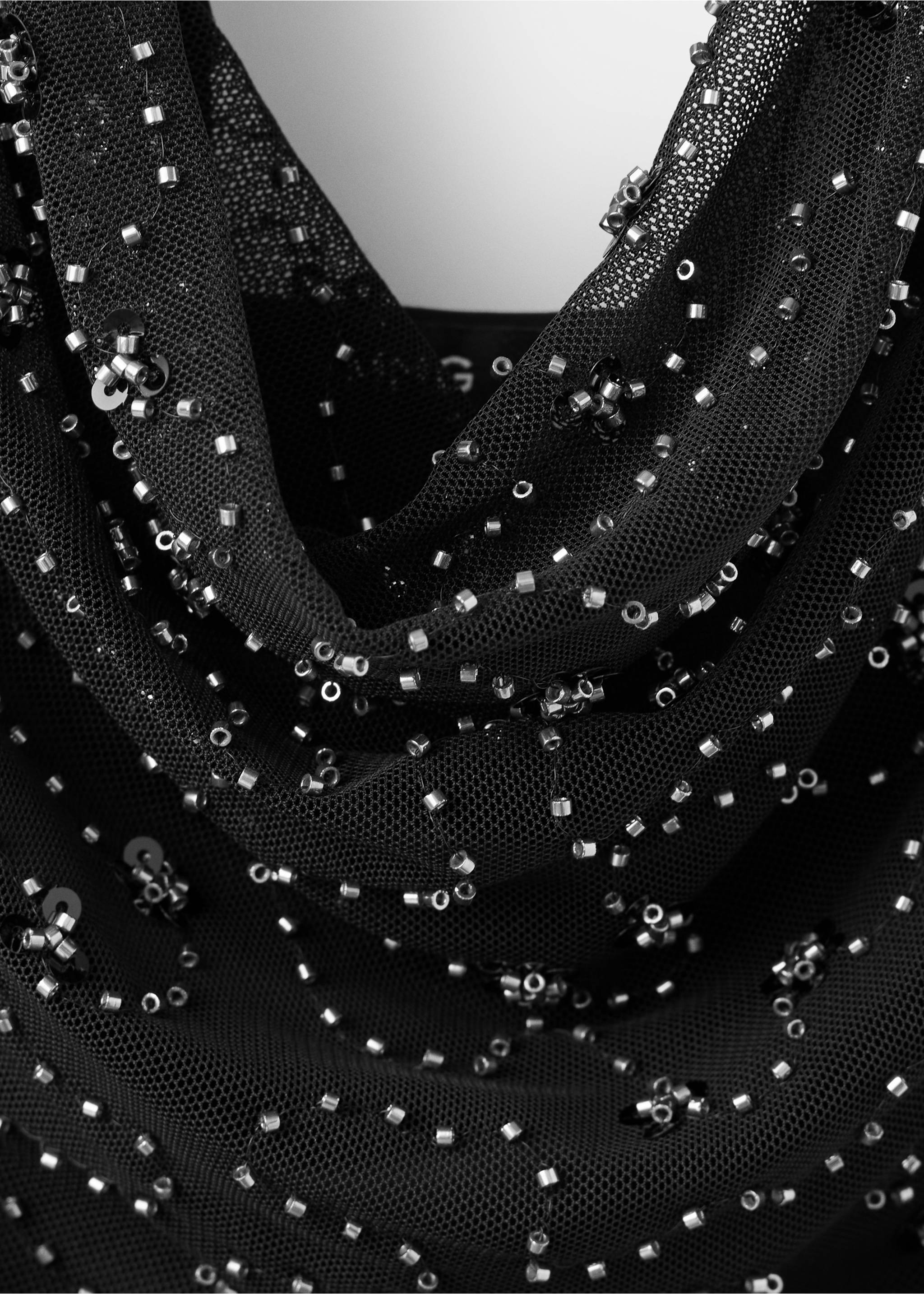 Close-up of a black mesh top with a cowl neck embellished with silver beads., Black. Ref: 37019130-00.