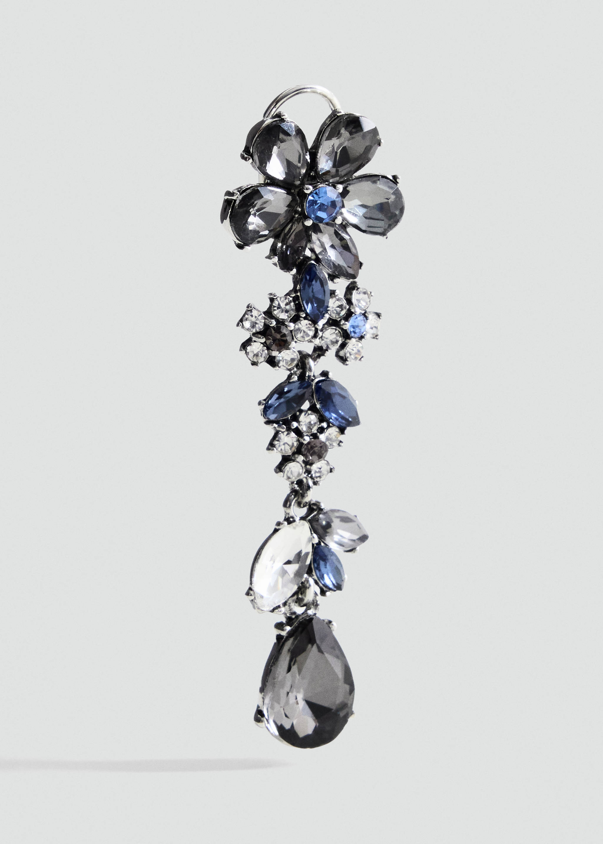 Close-up of a cascading rhinestone flower and drop earring in grey and blue tones.