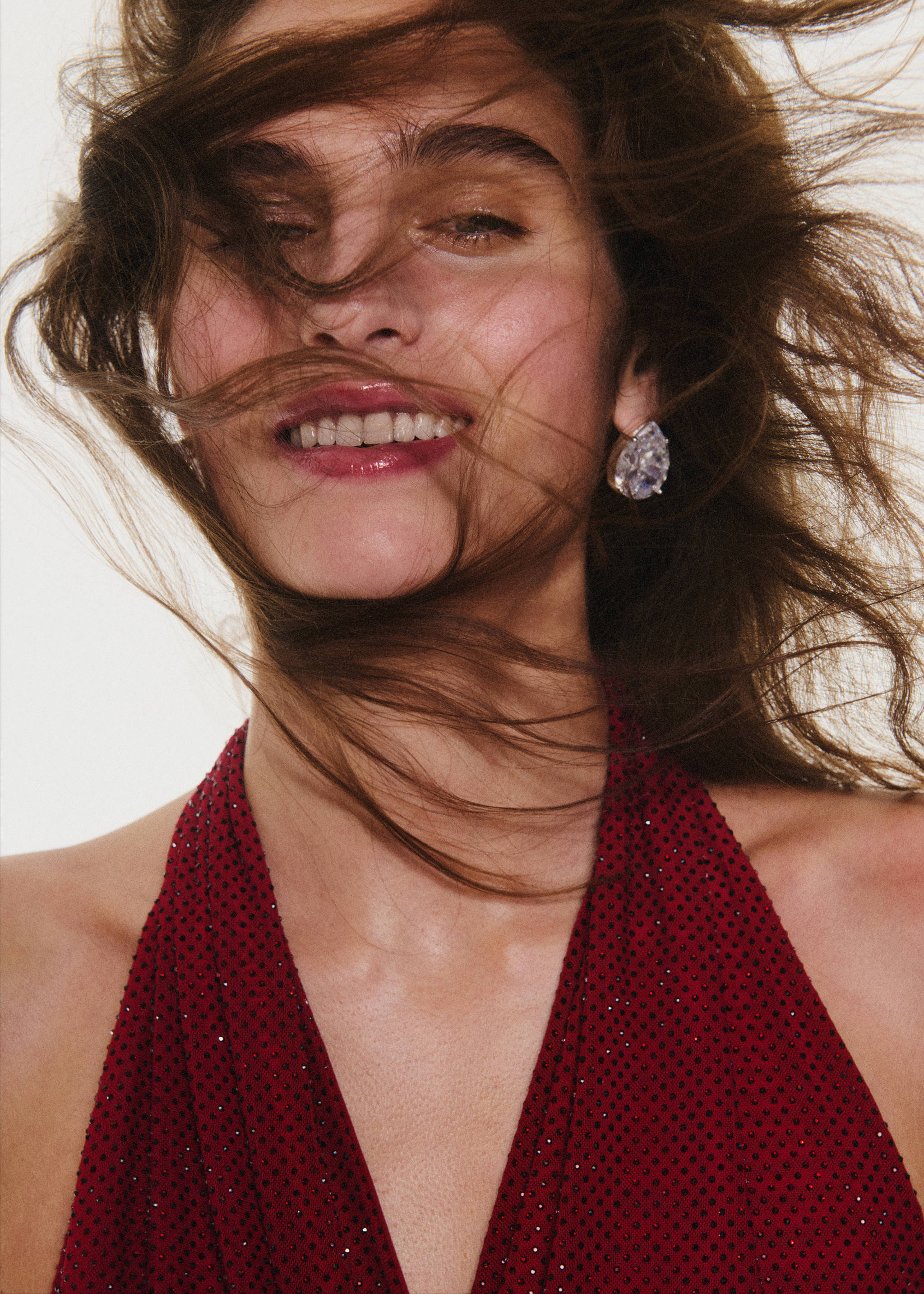 Faceted teardrop crystal earring worn with a dark red halter top.