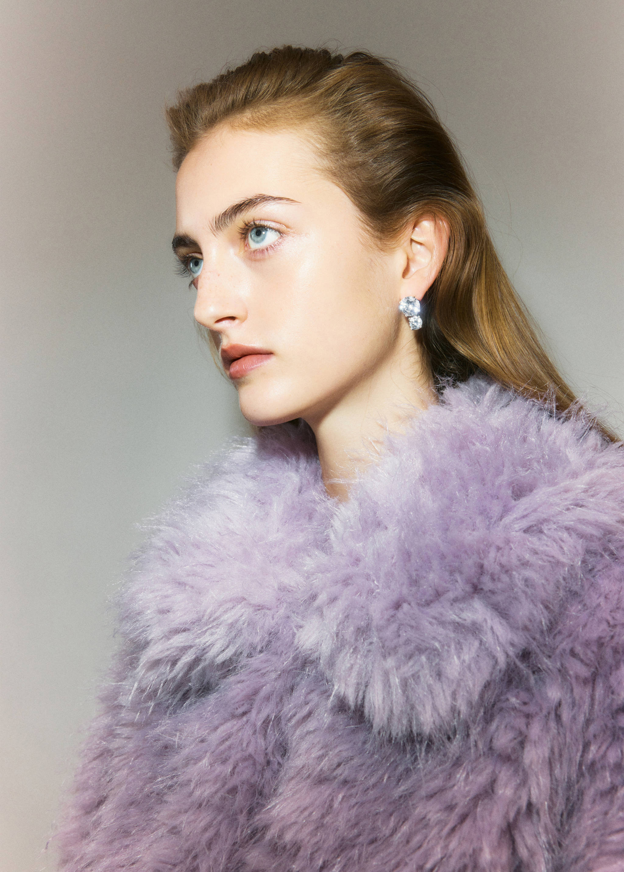 Crystal cluster earrings worn on a model in a lilac faux-fur coat.